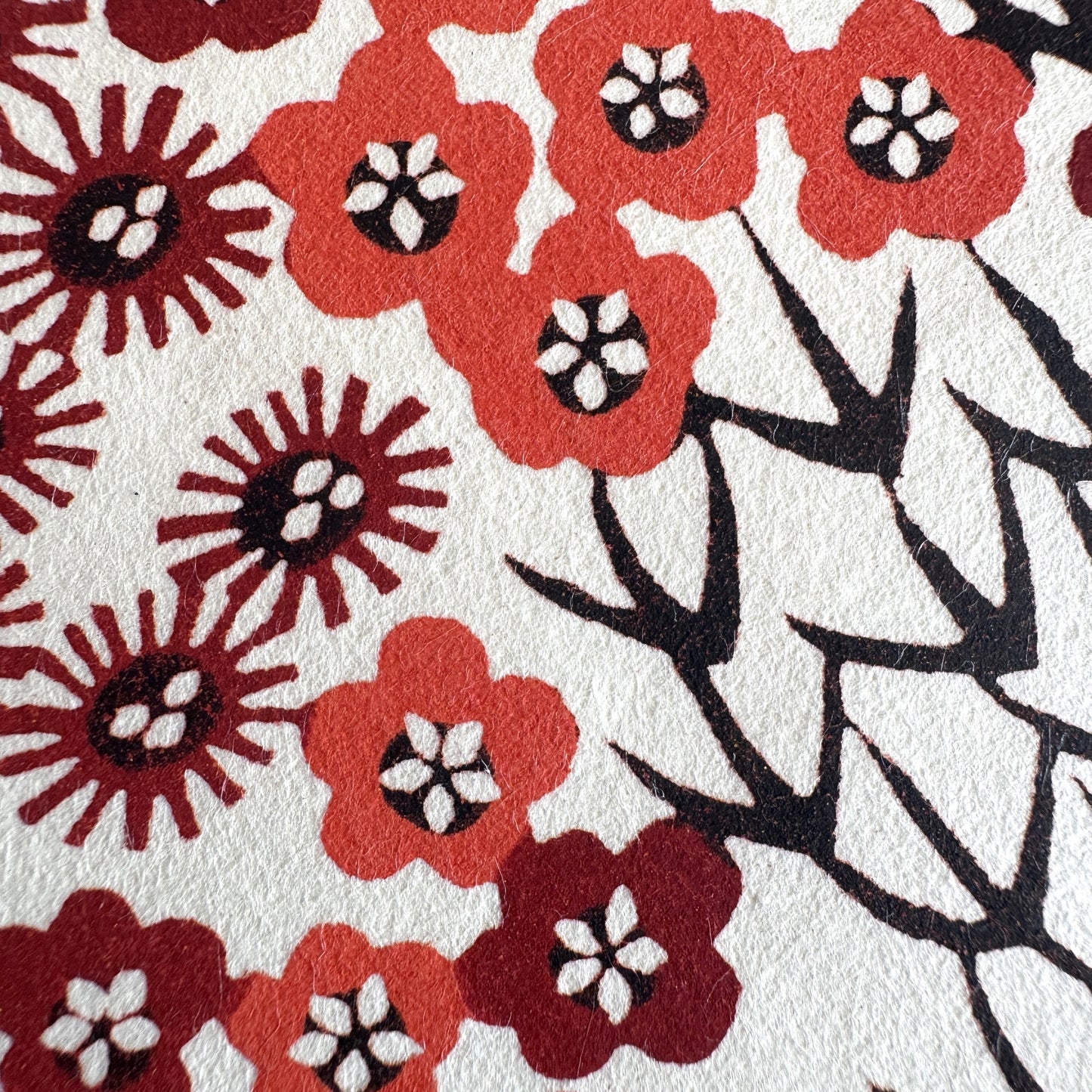 Japanese katazome-shi paper stencil -dyed with a small red flower design, little black stems on ivory paper. Very detailed close-up