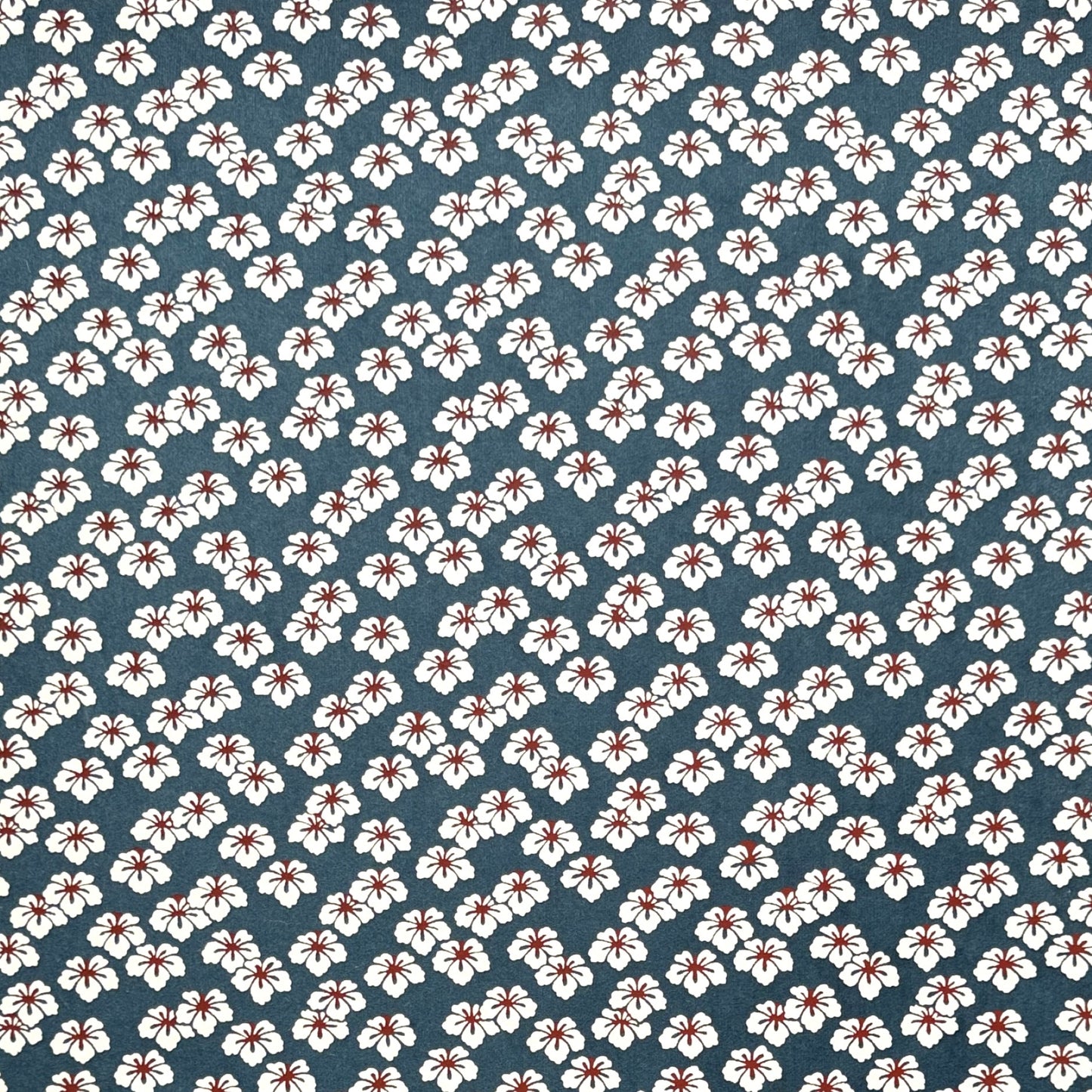 Japanese katazome-shi paper stencil-dyed with a small flower pattern in inky blue, white and red.
