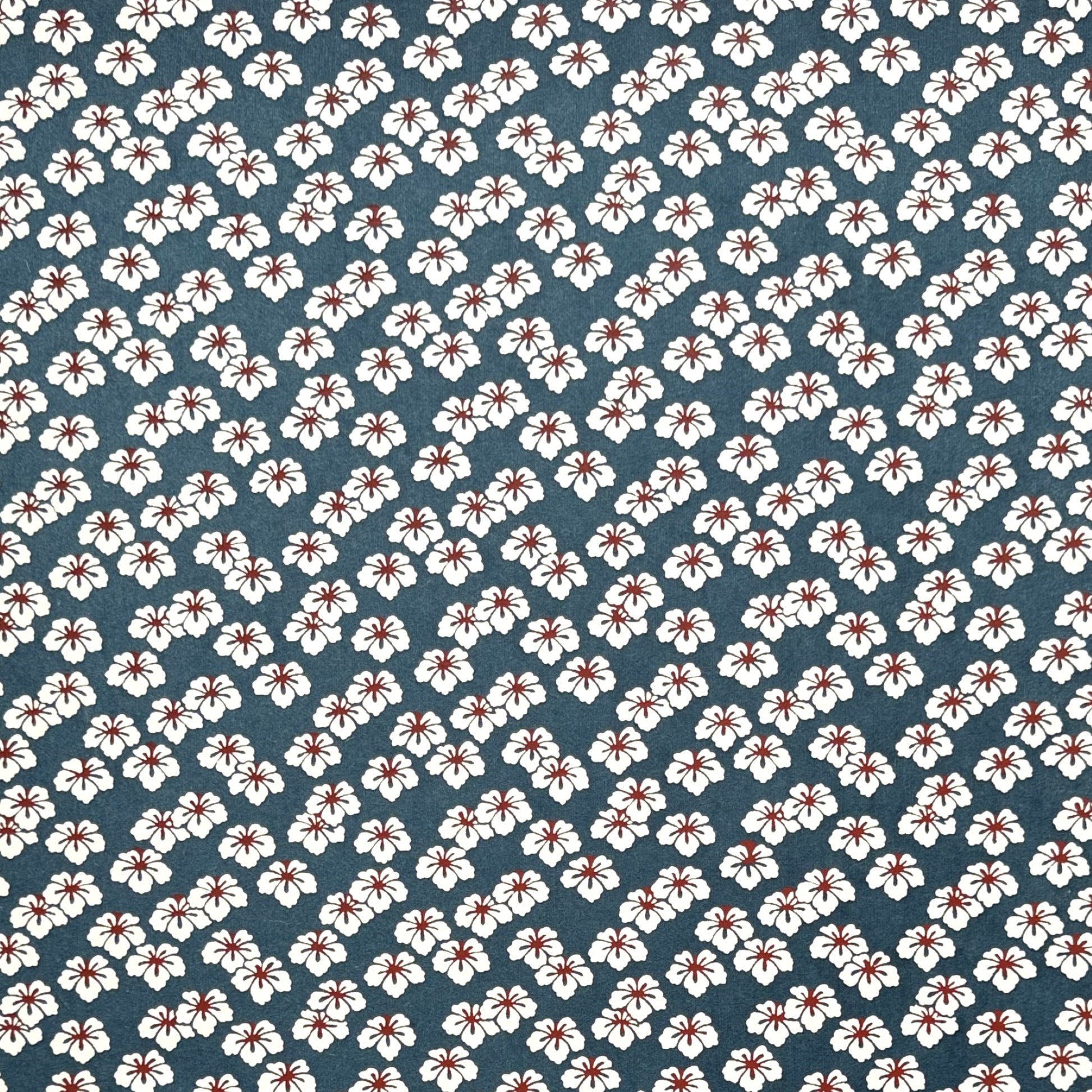 Japanese katazome-shi paper stencil-dyed with a small flower pattern in inky blue, white and red.