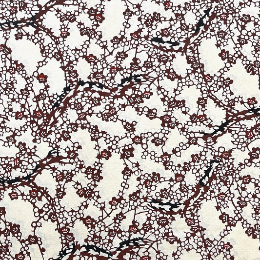 Japanese kazazome-shi stenciled dyed paper with a pattern of branches of plum blossom in deep maroon and black on an ivory paper.