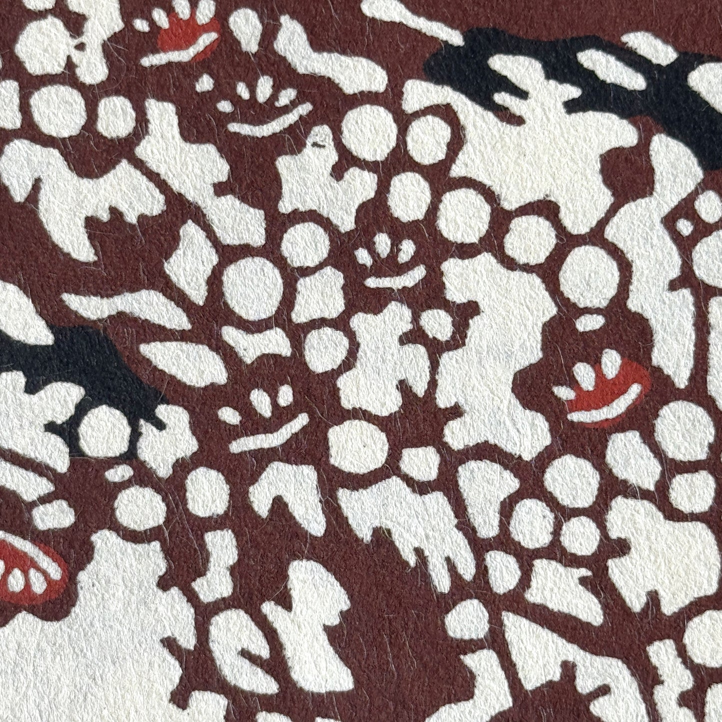 Japanese kazazome-shi stenciled dyed paper with a pattern of branches of plum blossom in deep maroon and black on an ivory paper. Very detailed close-up