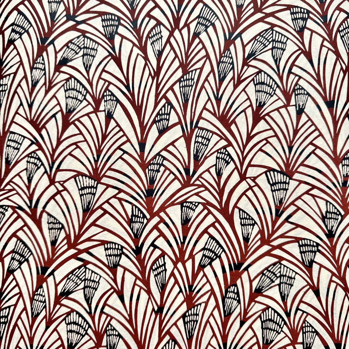 Japanese katazome-shi stencil-dyed paper with a fan-like pattern in deep maroon and black on cream paper.