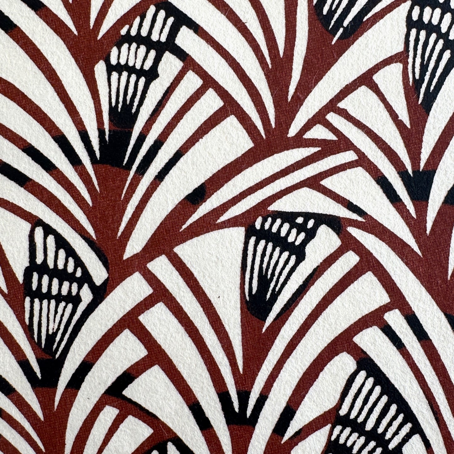 Japanese katazome-shi stencil-dyed paper with a fan-like pattern in deep maroon and black on cream paper. Very detailed close-up