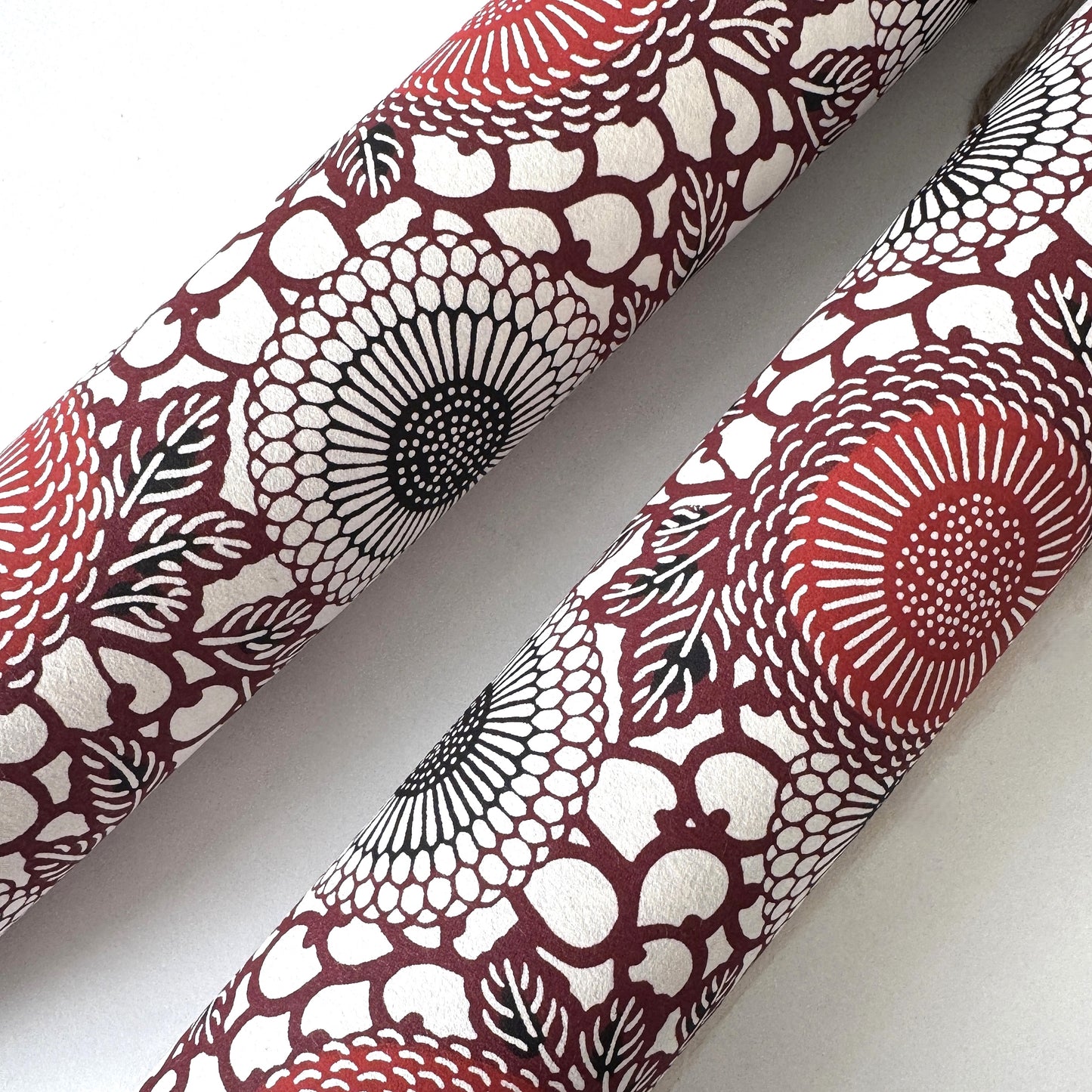 Japanese katazome-shi paper stencil-dyed with a pattern of stylised kiko flowers in red, maroon and black on an ivory paper. Rolled