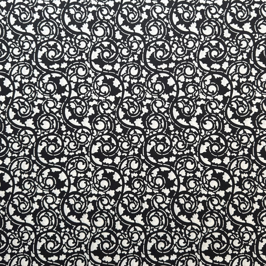 Japanese katazome-shi paper with bold black arabesque vines (karakusa) pattern on an ivory paper.
