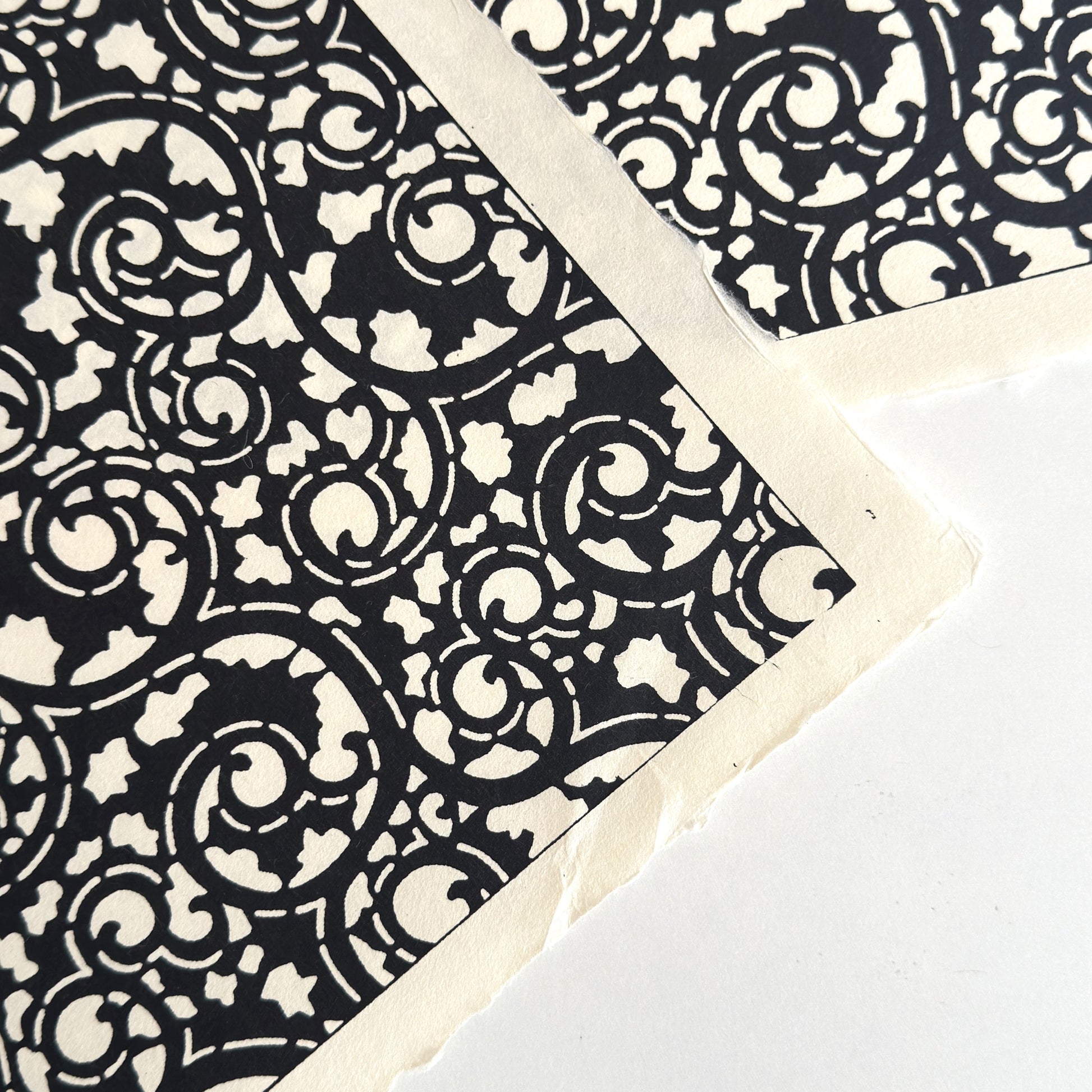 Japanese katazome-shi paper with bold black arabesque vines (karakusa) pattern on an ivory paper.  Close up