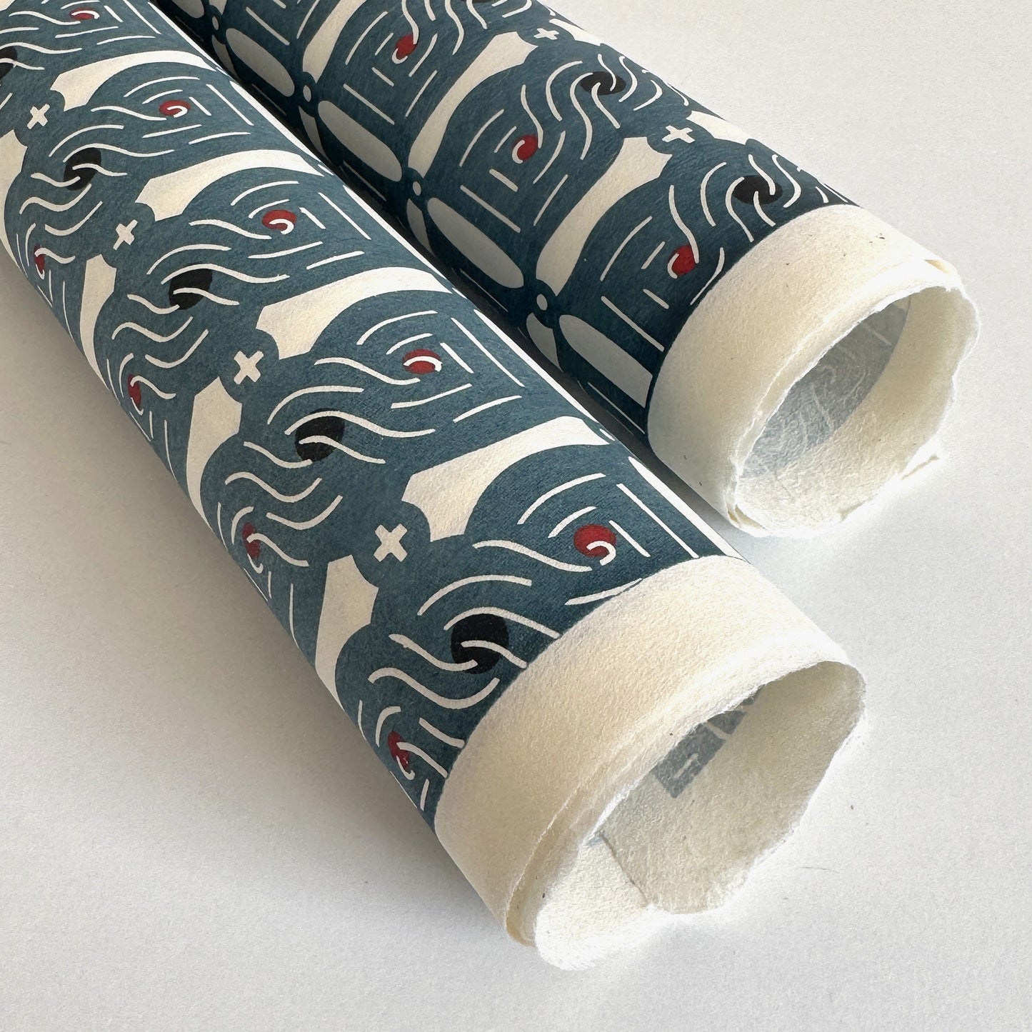 Japanese katazome stencil dyed paper with a repeat pattern of muted blue knots. Close up of the deckle-edges