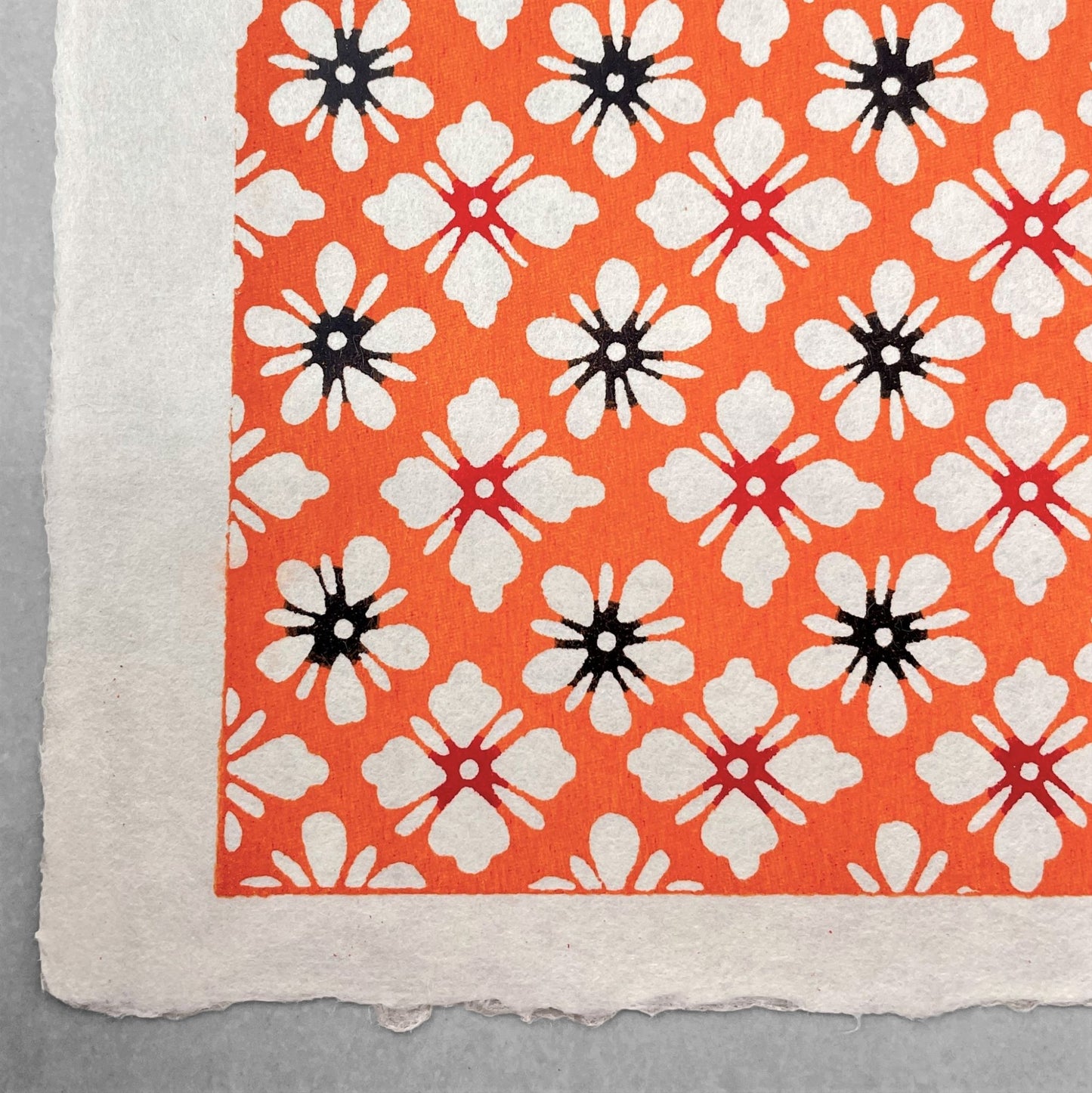 japanese stencil-dyed handmade paper with small scale floral repeat in orange and cream