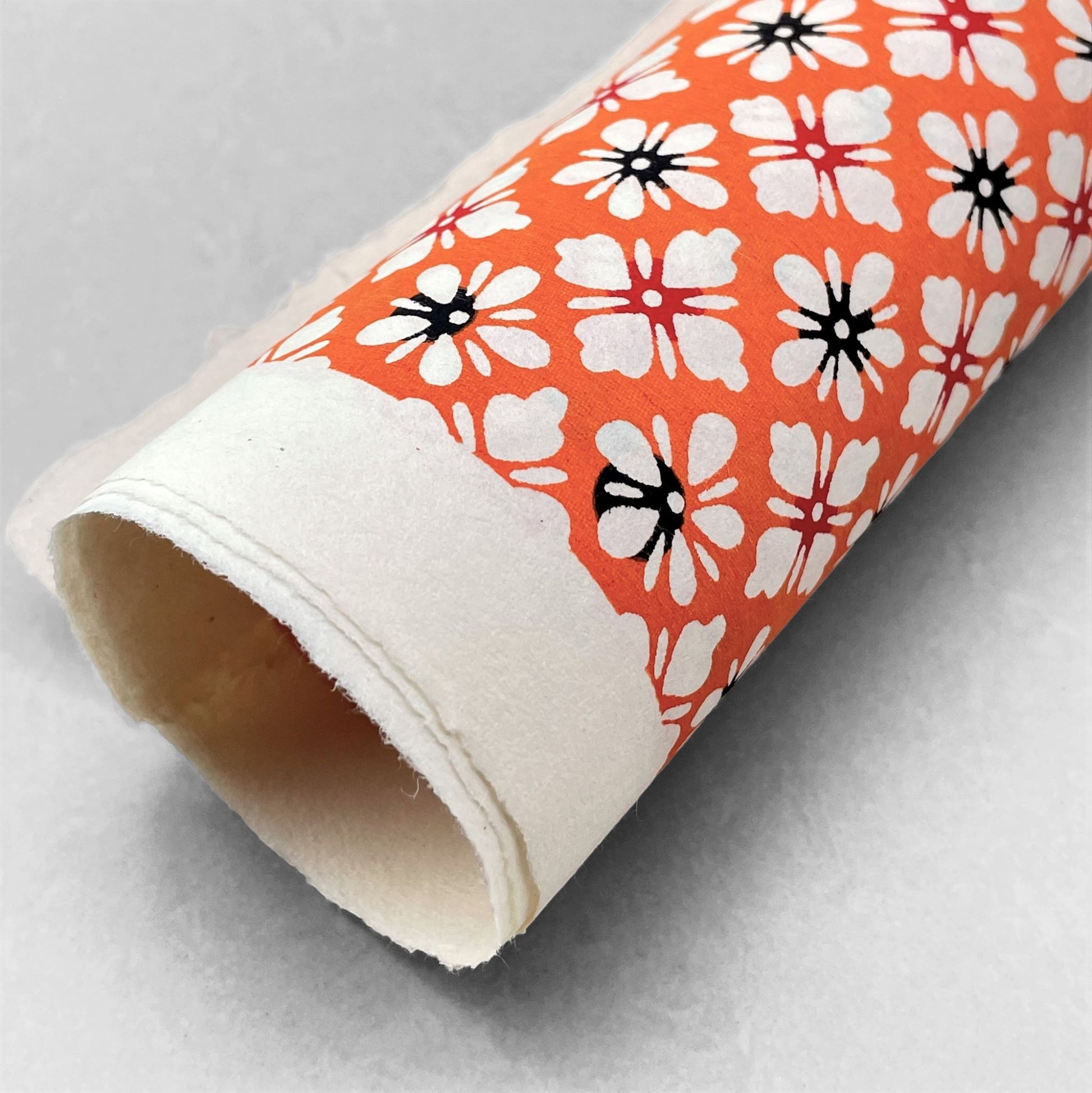 japanese stencil-dyed handmade paper with small scale floral repeat in orange and cream