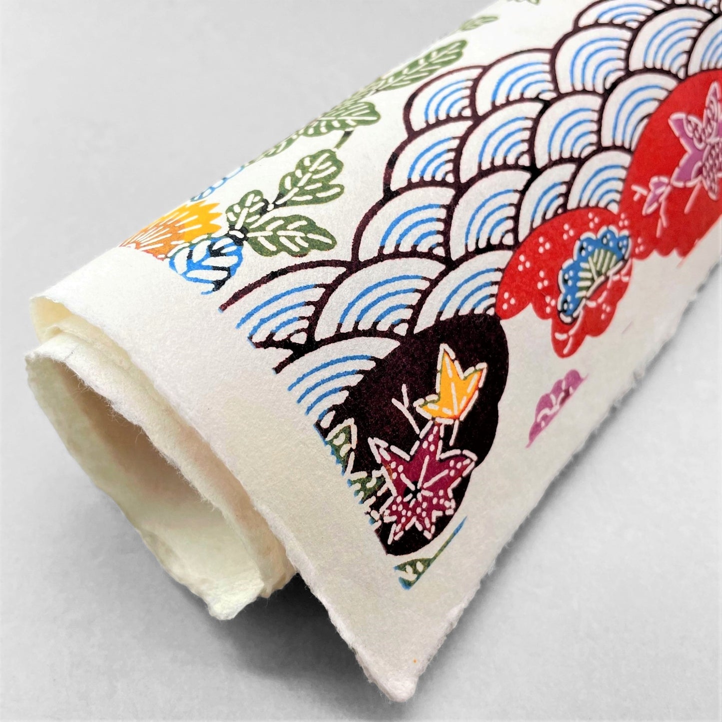 japanese stencil-dyed handmade paper with traditional botanical pattern in red, brown, yellow and blue