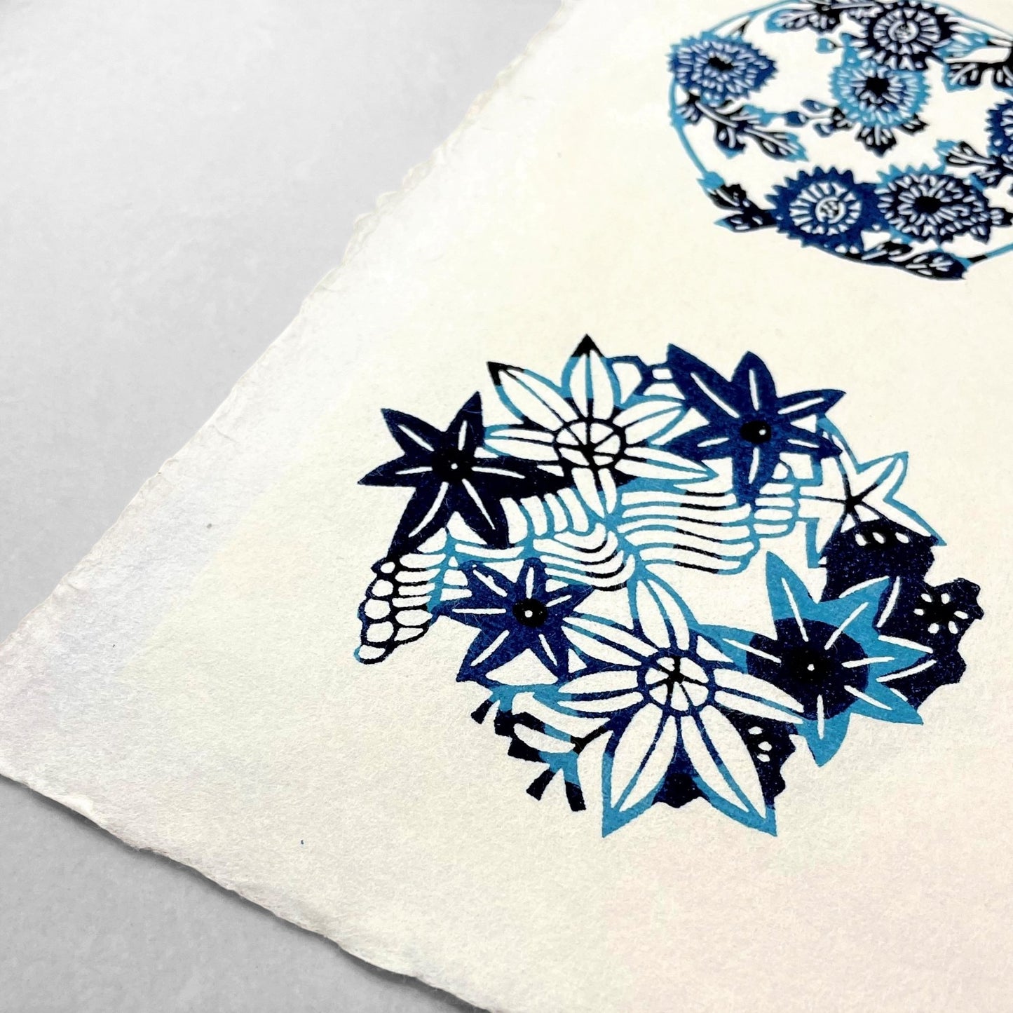 japanese stencil-dyed handmade paper with traditional blue botanical circles pattern on ivory backdrop