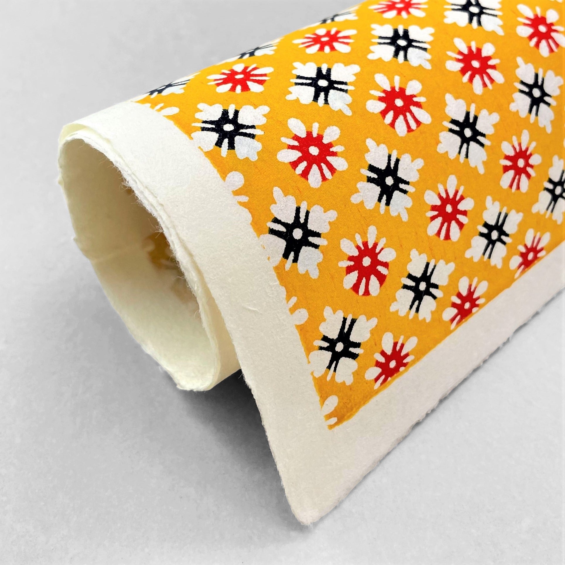 japanese stencil-dyed handmade paper with small scale floral repeat pattern on yellow backdrop