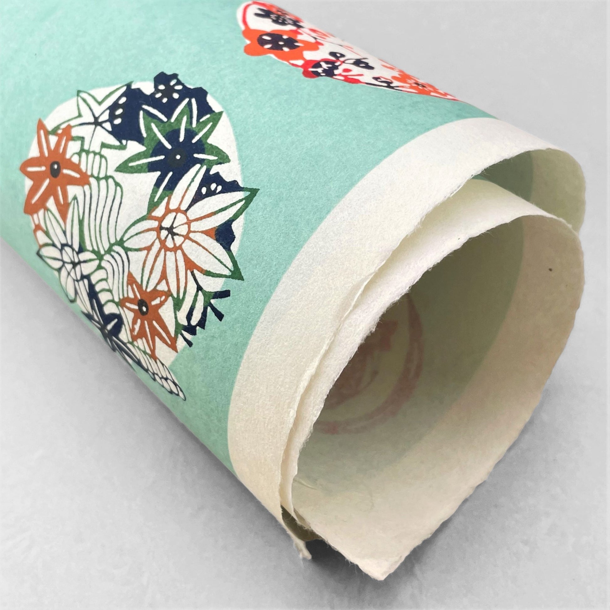japanese stencil-dyed handmade paper with traditional botanical circles pattern on aqua backdrop