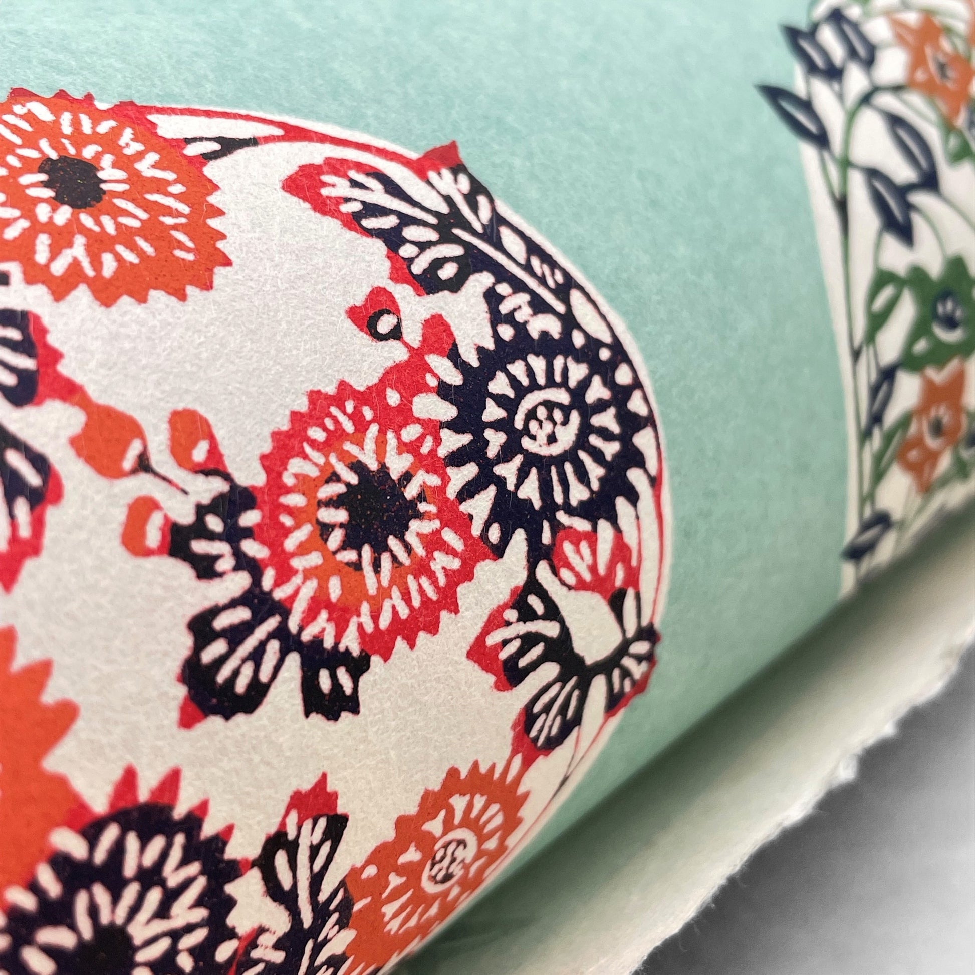 japanese stencil-dyed handmade paper with traditional botanical circles pattern on aqua backdrop