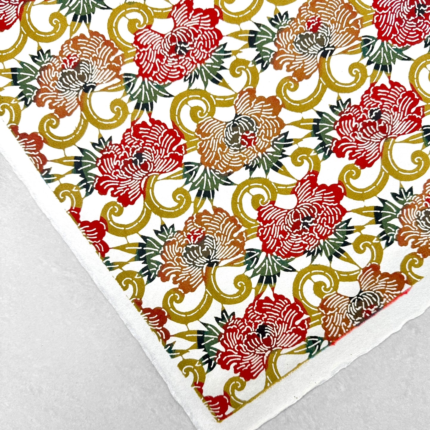 Japanese Katazome-shi stencil-dyed paper with repeat pattern on stylised peonies in autumnal colours. Close up of corner