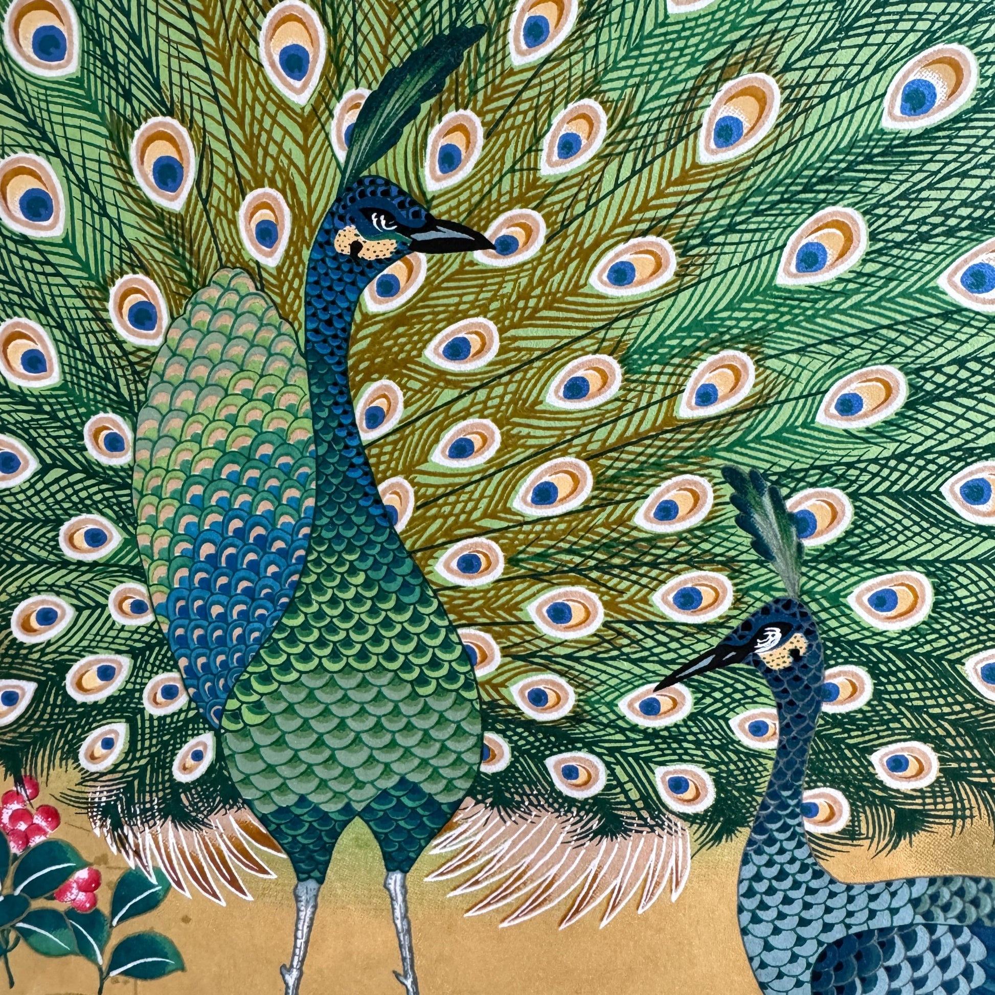 A sheet of Japanese silkscreen printed paper called Sogara which depicts white cranes flying in a pink and gold sky, surrounded by blossom and flowers. Close up of the peacock feathers