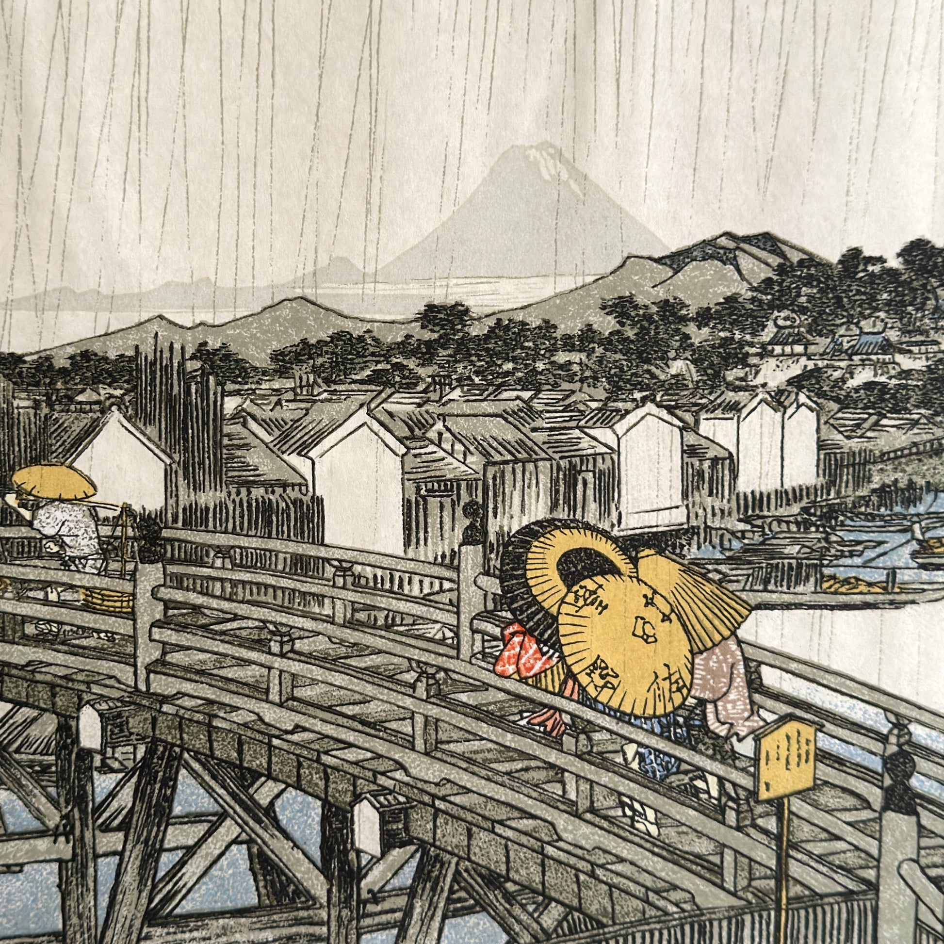 A sheet of Japanese Sogara silkscreen printed paper with 4 images from artwork by Hiroshige.  Close up of people crossing a bridge with umbrellas in a storm