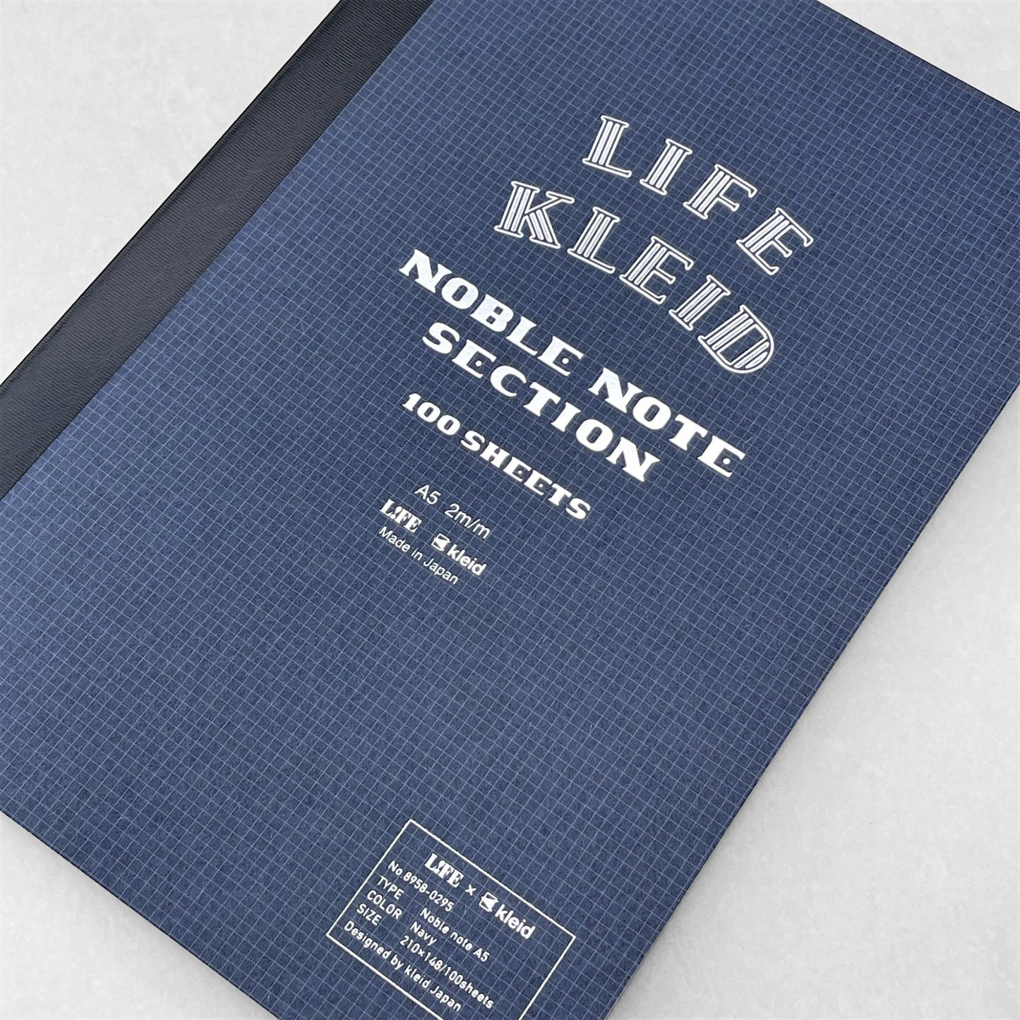 A5 softcover notebook with grid pages. The cover is dark blue with a white grid, black spine and branding in silver. By Japanese brand Kleid