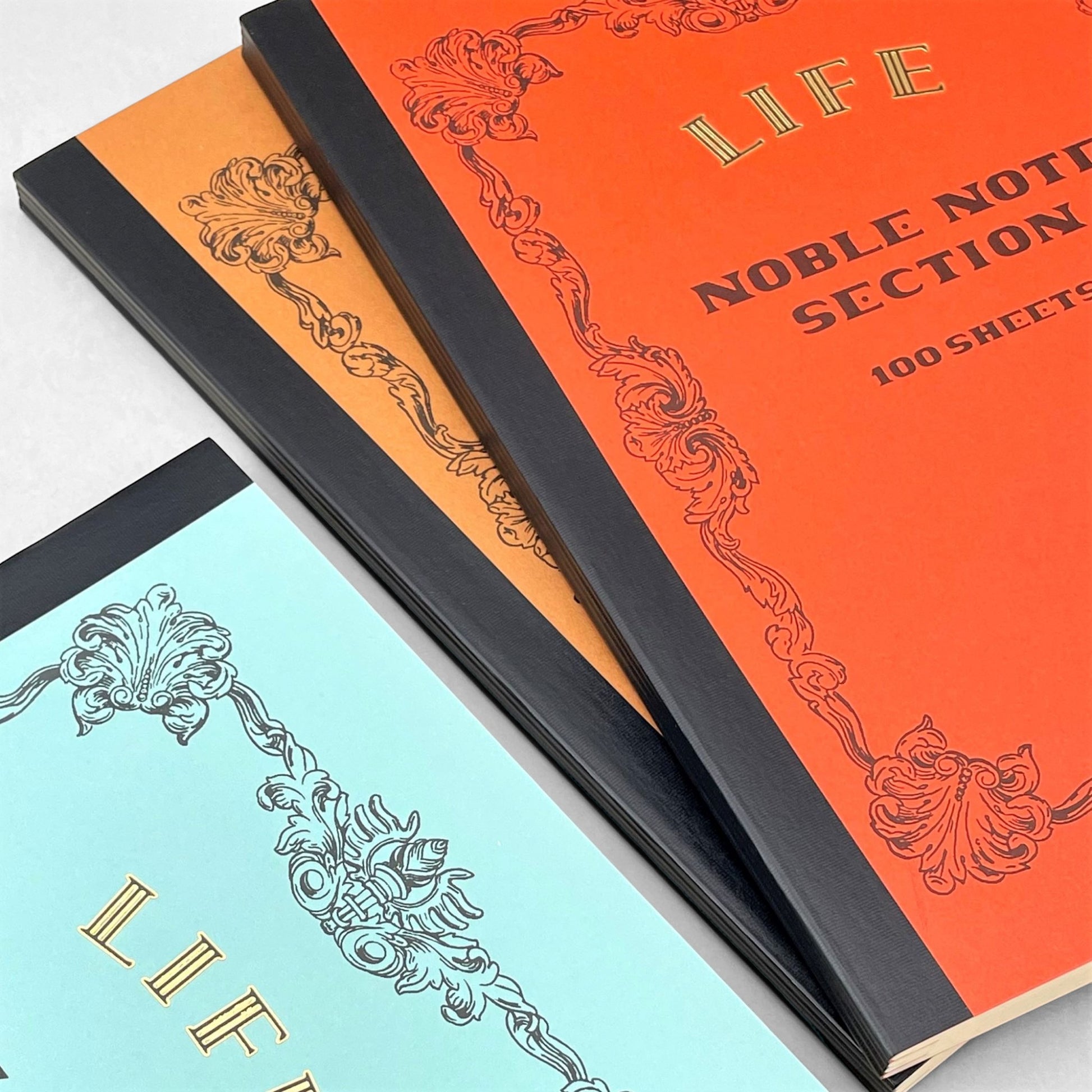 Softcover notebook with grid pages. The cover is plain red with a decorative black border and branding. Life Noble range by Japanese brand Life