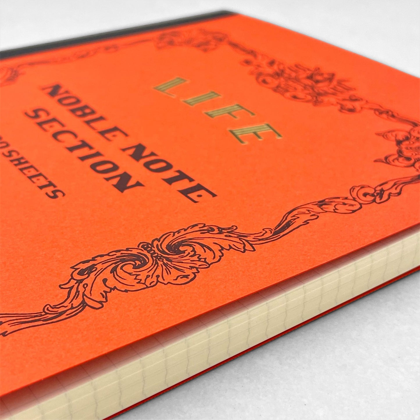 Softcover notebook with grid pages. The cover is plain red with a decorative black border and branding. Life Noble range by Japanese brand Life
