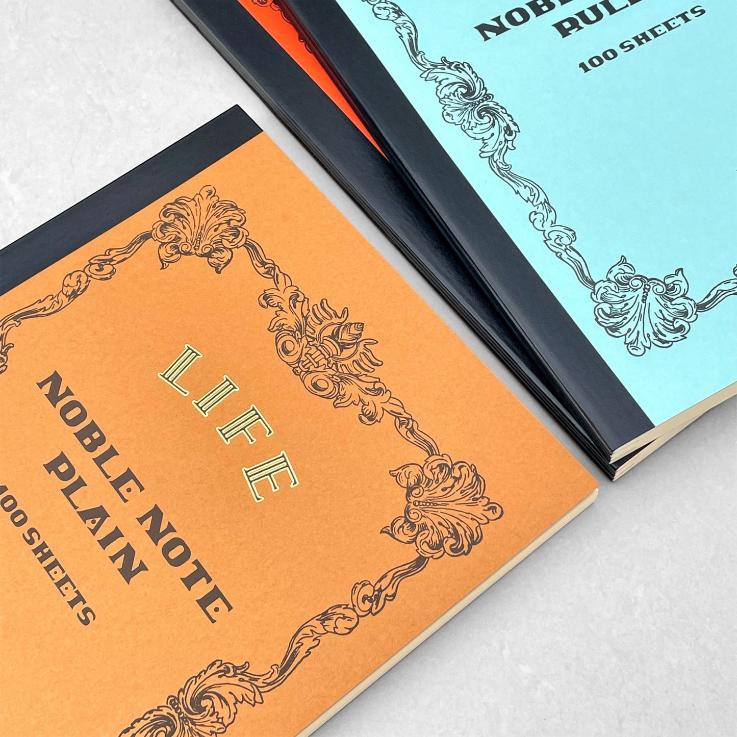 Softcover notebook with plain pages. The cover is plain ochre with a decorative black border and branding. Life Noble range by Japanese brand Life