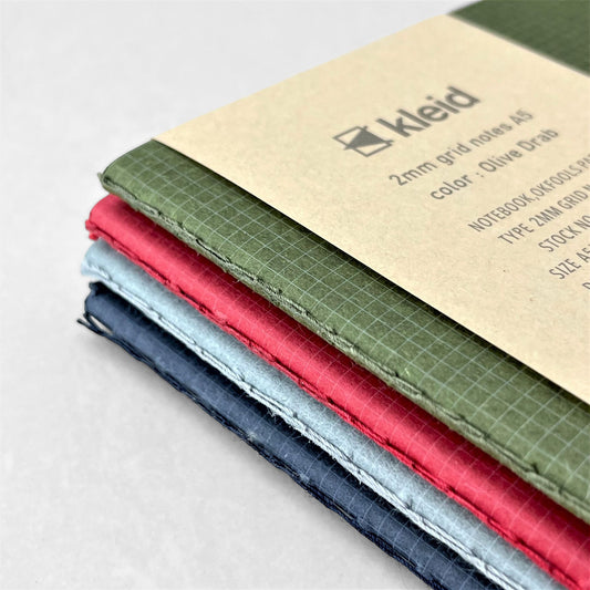 A5 soft cover notebook, cover is olive green with a small white grid pattern by Japanese brand Kleid