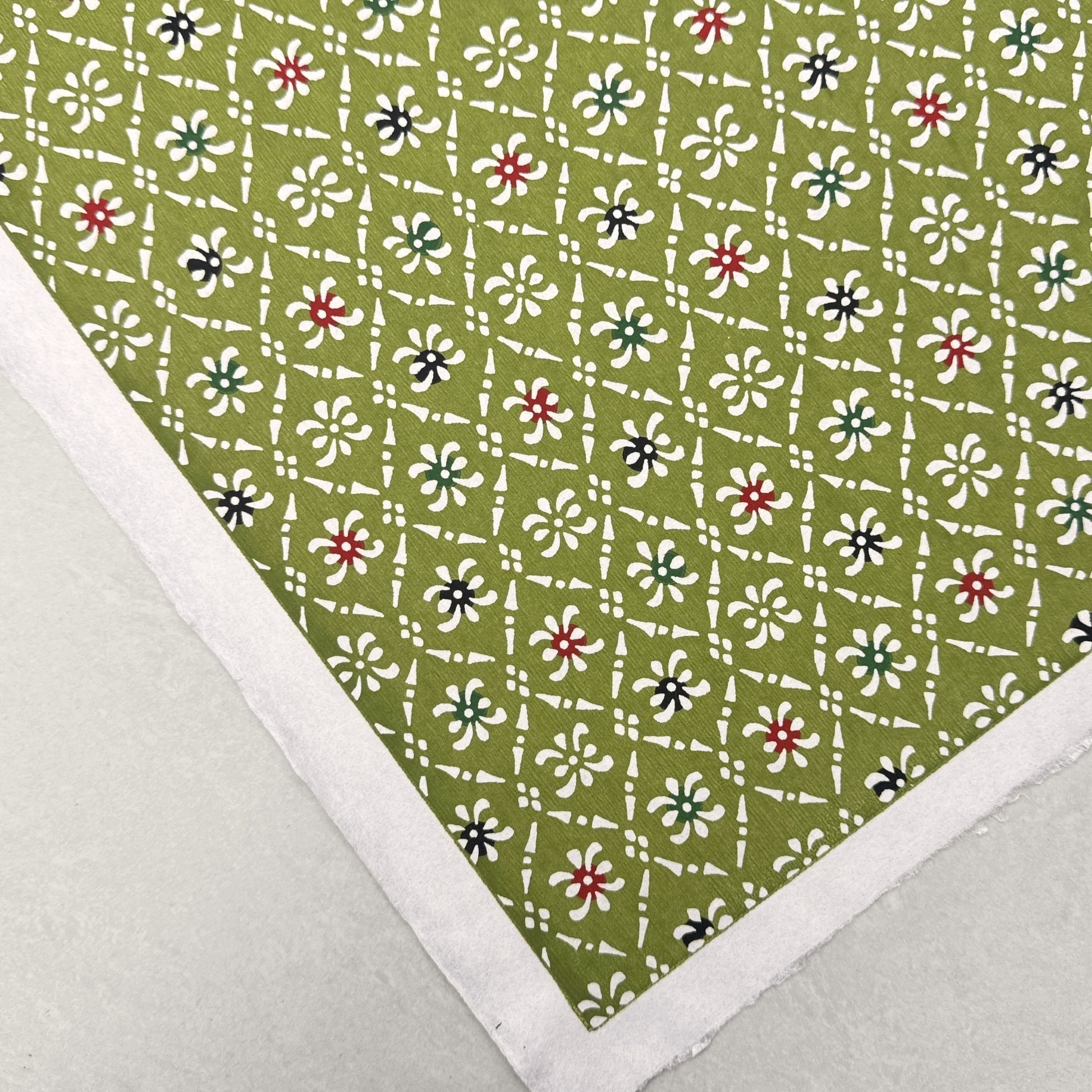 Japanese stencil-dyed katazome-shi paper with a white geometric pattern on green backdrop.