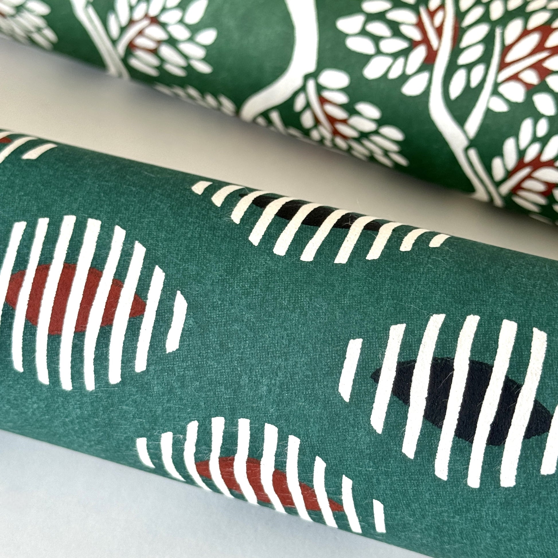 japanese stencil-dyed paper with geometric oval pattern in white, black and red on green background. Close up rolled