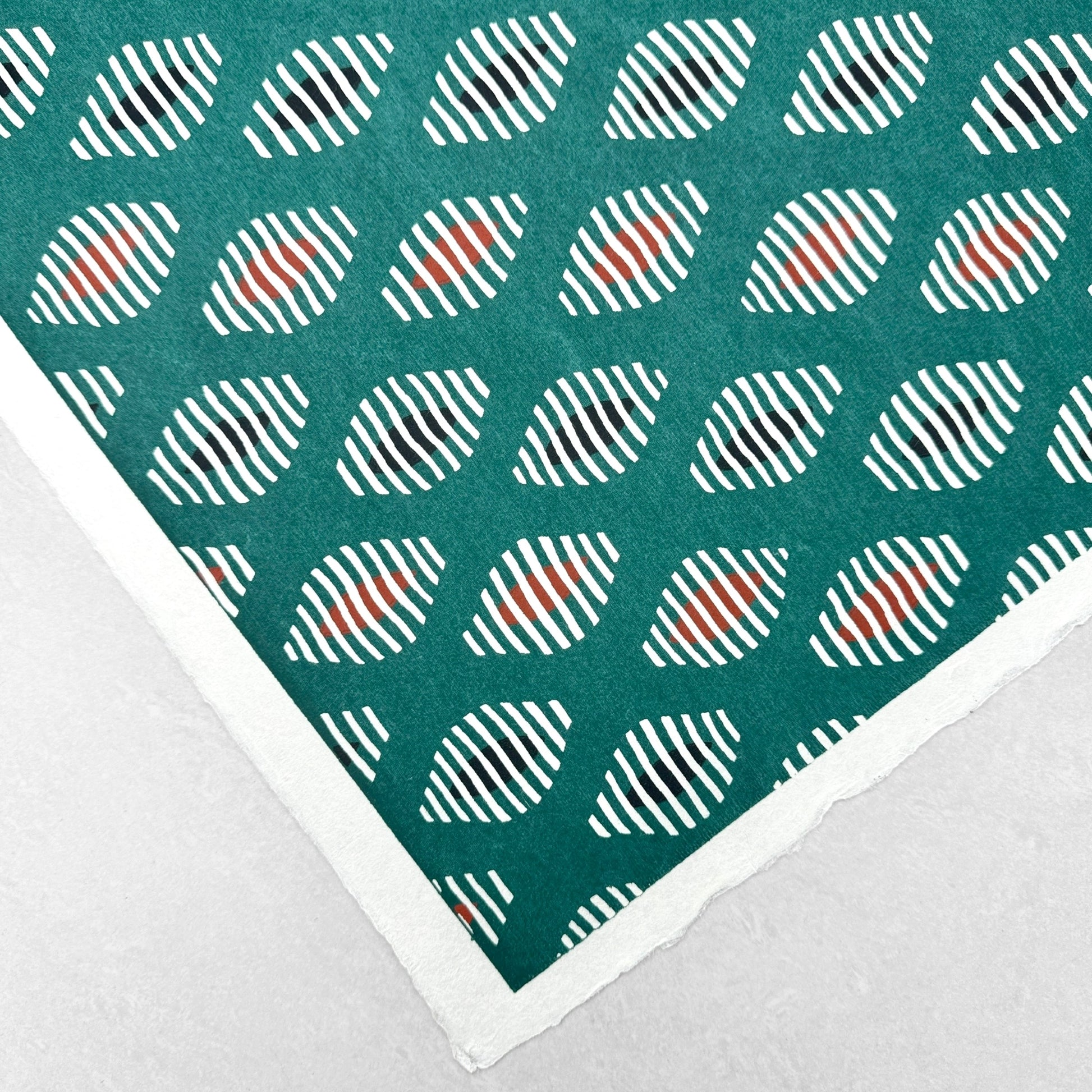 japanese stencil-dyed paper with geometric oval pattern in white, black and red on green background