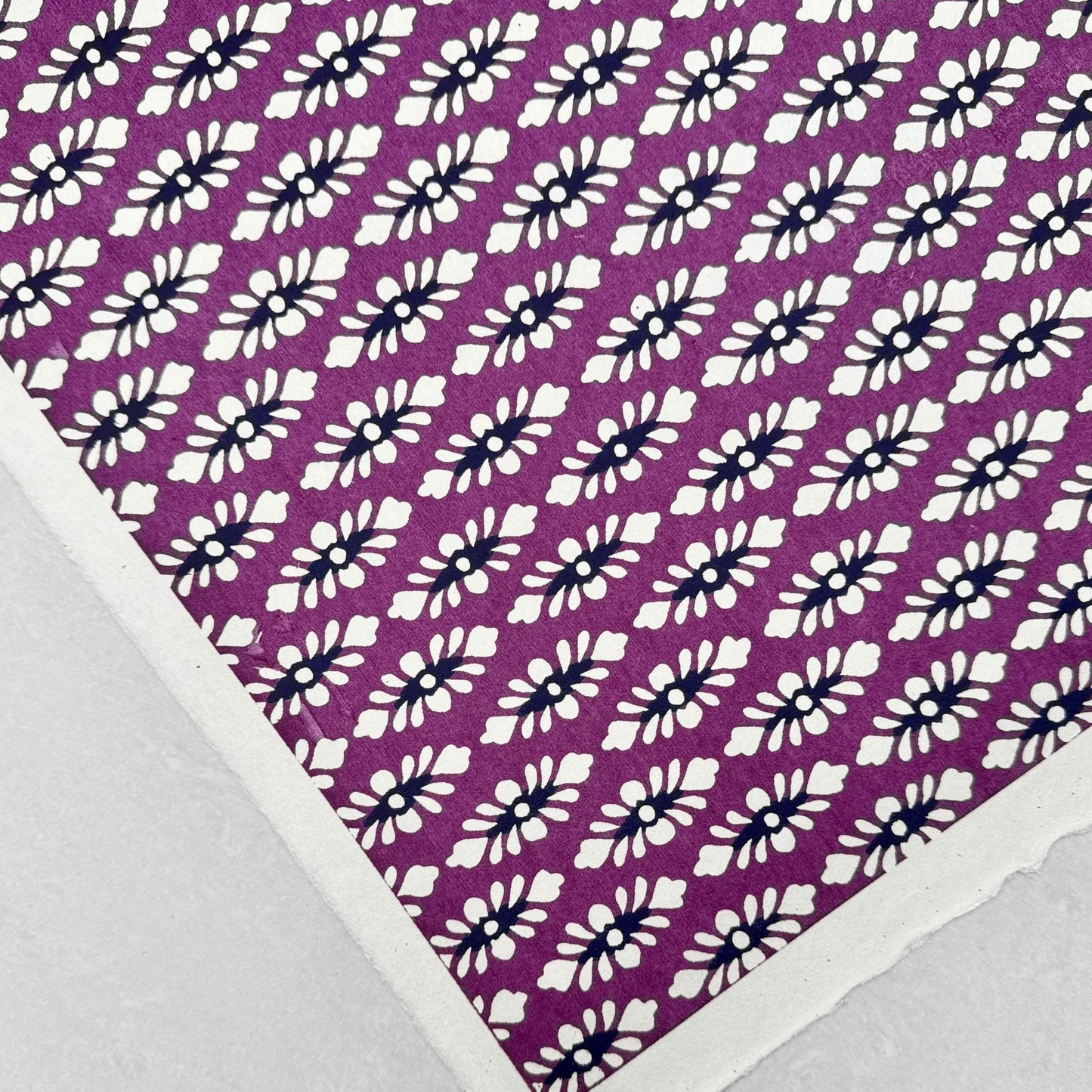 japanese katazome-shi paper (stencil-dyed) with a white and black repeat pattern on purple. Close up