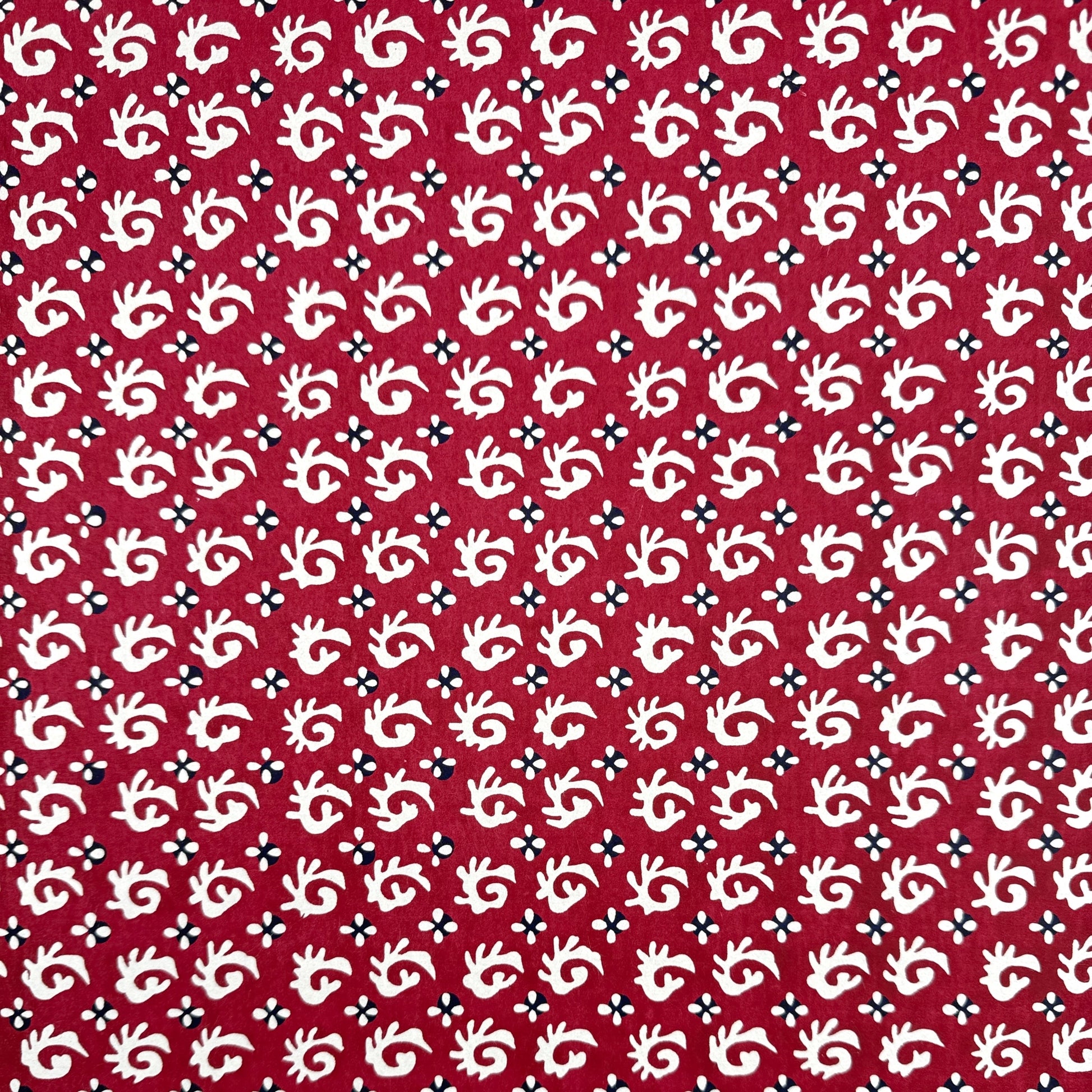 A Japanese stencil-dyed patterned paper with a repeat pattern in white on a deep rich red background.