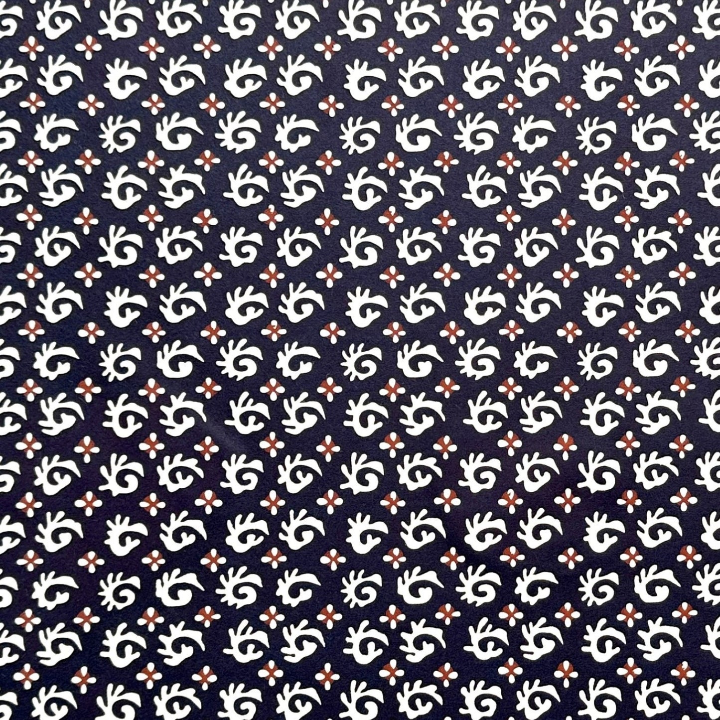 japanese stencil-dyed paper with a white swirl geometric repeat pattern on a dark inky blue background