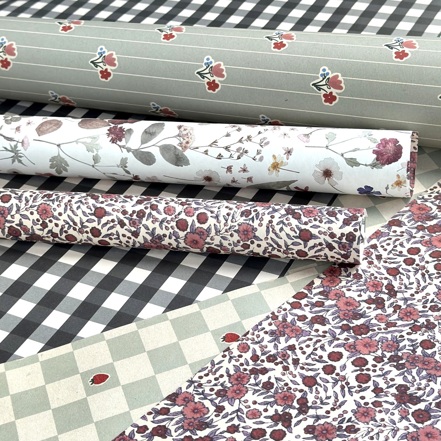 rolls of wrapping paper by designer Katie Leamon in botanical floral patterns , checks and stripes