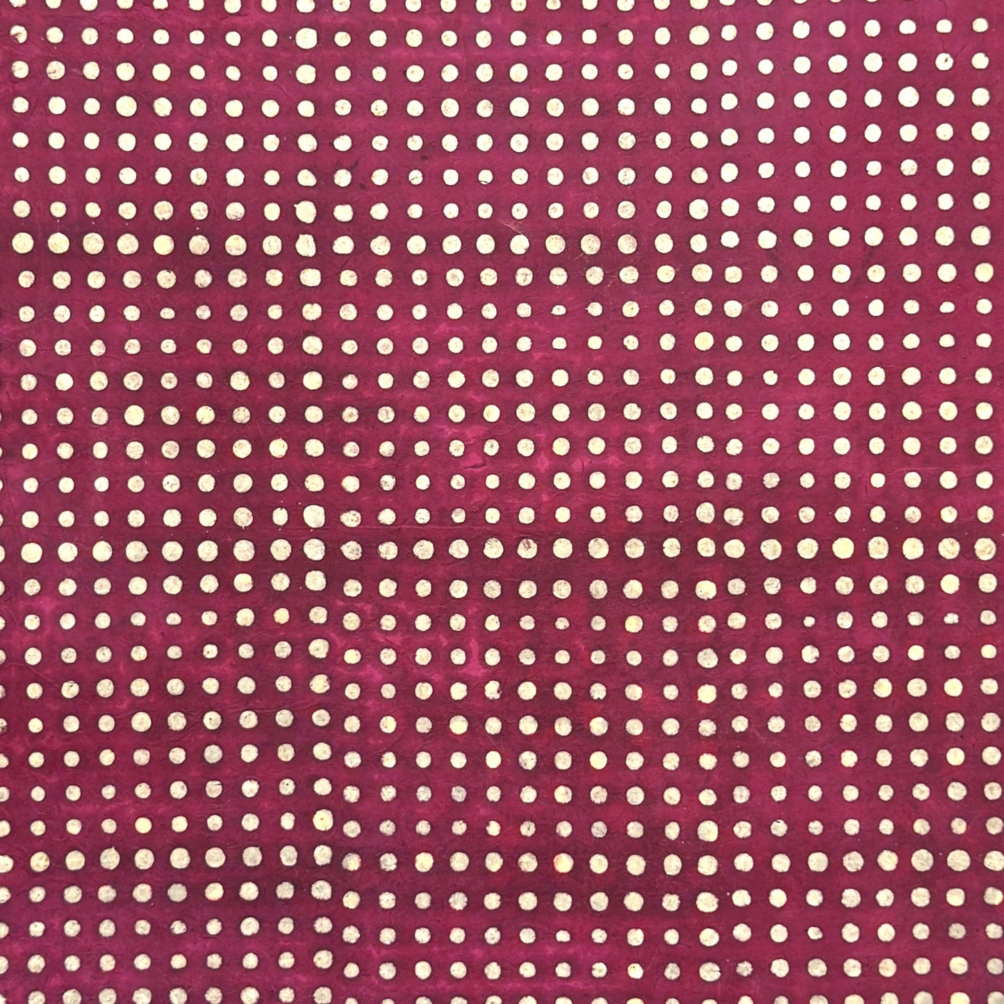 Nepalese handmade decorative lokta paper sheet with a pattern of white dots on burgundy red lokta paper.  Batik dyed using carved wooden blocks.