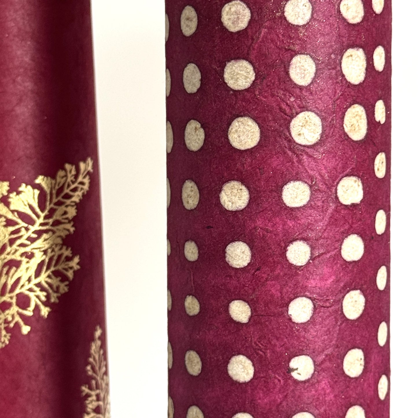 Nepalese handmade decorative lokta paper sheet with a pattern of white dots on burgundy red lokta paper.  Batik dyed using carved wooden blocks. Close up