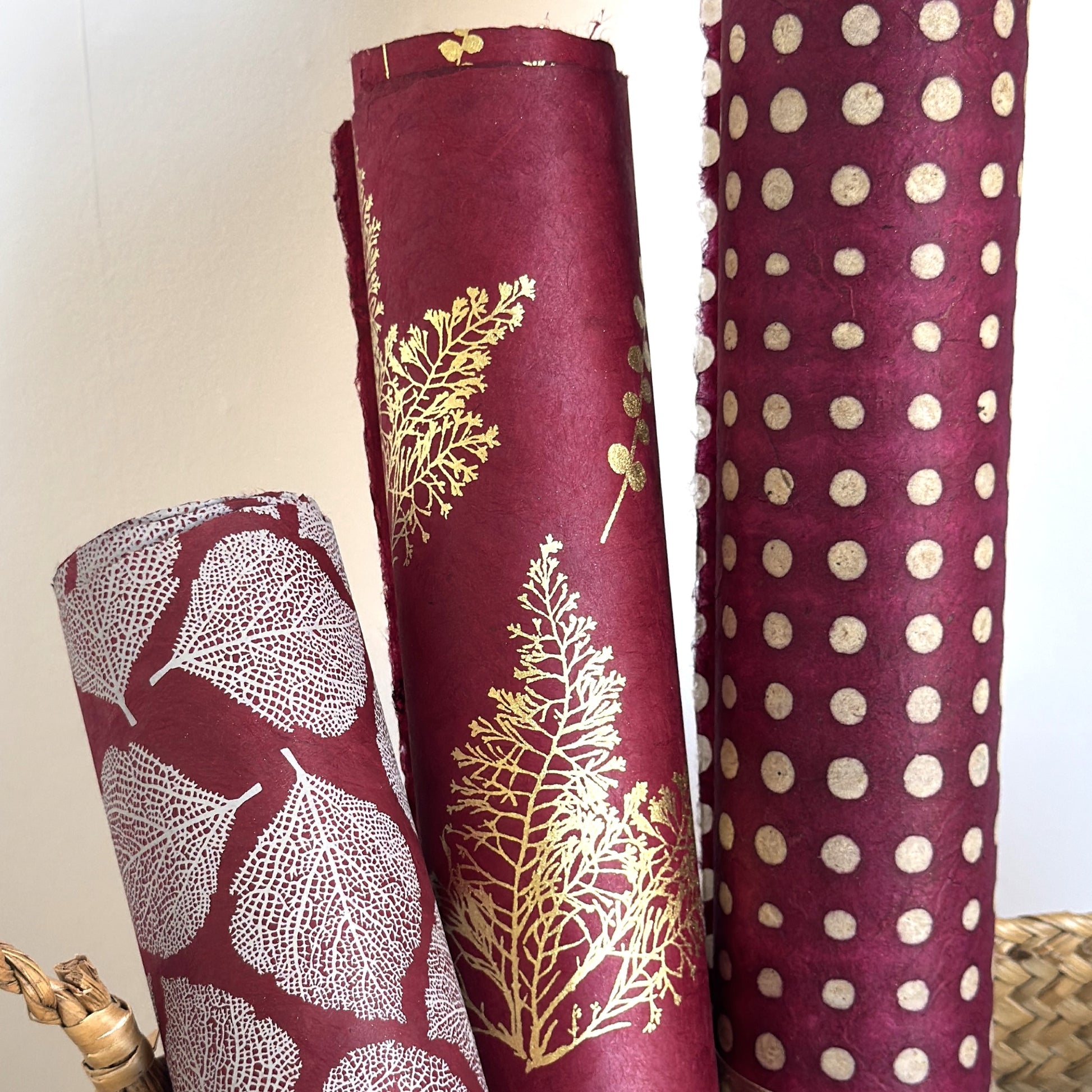 Nepalese handmade decorative lokta paper sheet with a pattern of white dots on burgundy red lokta paper.  Batik dyed using carved wooden blocks. Rolled