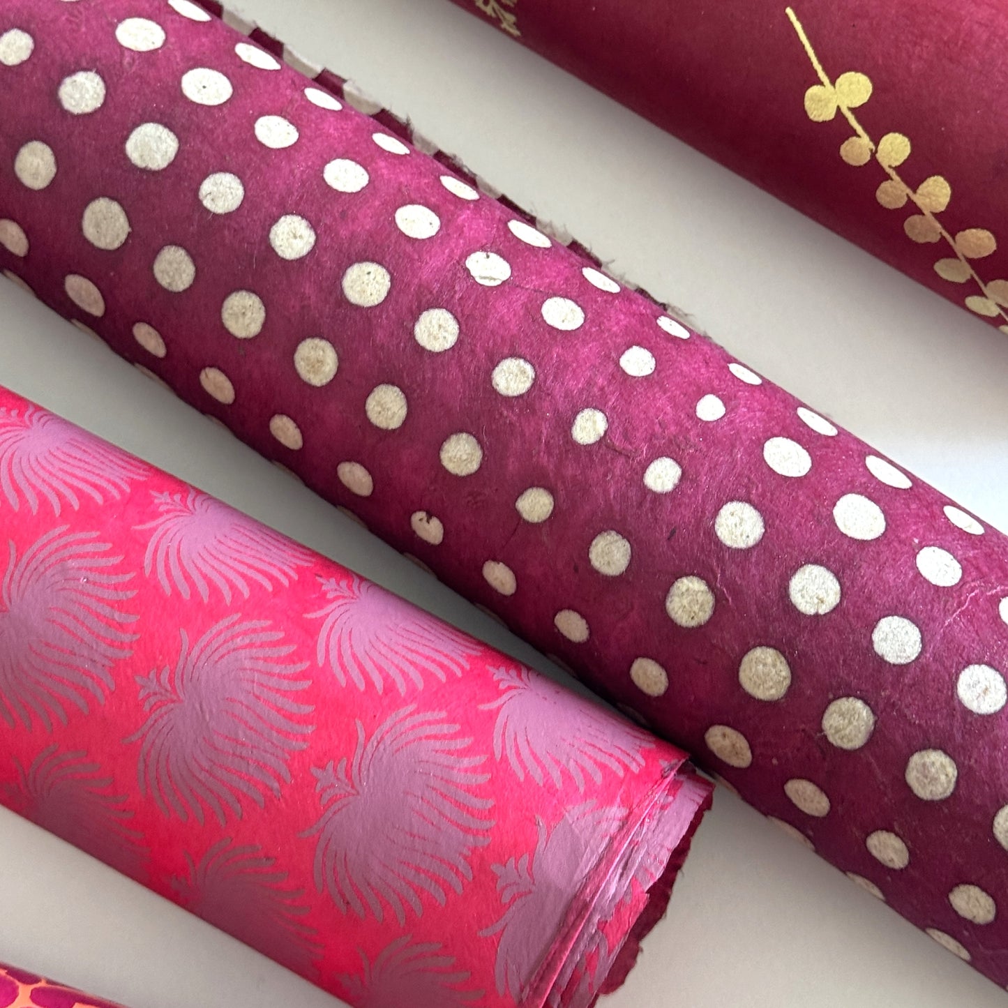 Nepalese handmade decorative lokta paper sheet with a pattern of white dots on burgundy red lokta paper.  Batik dyed using carved wooden blocks.