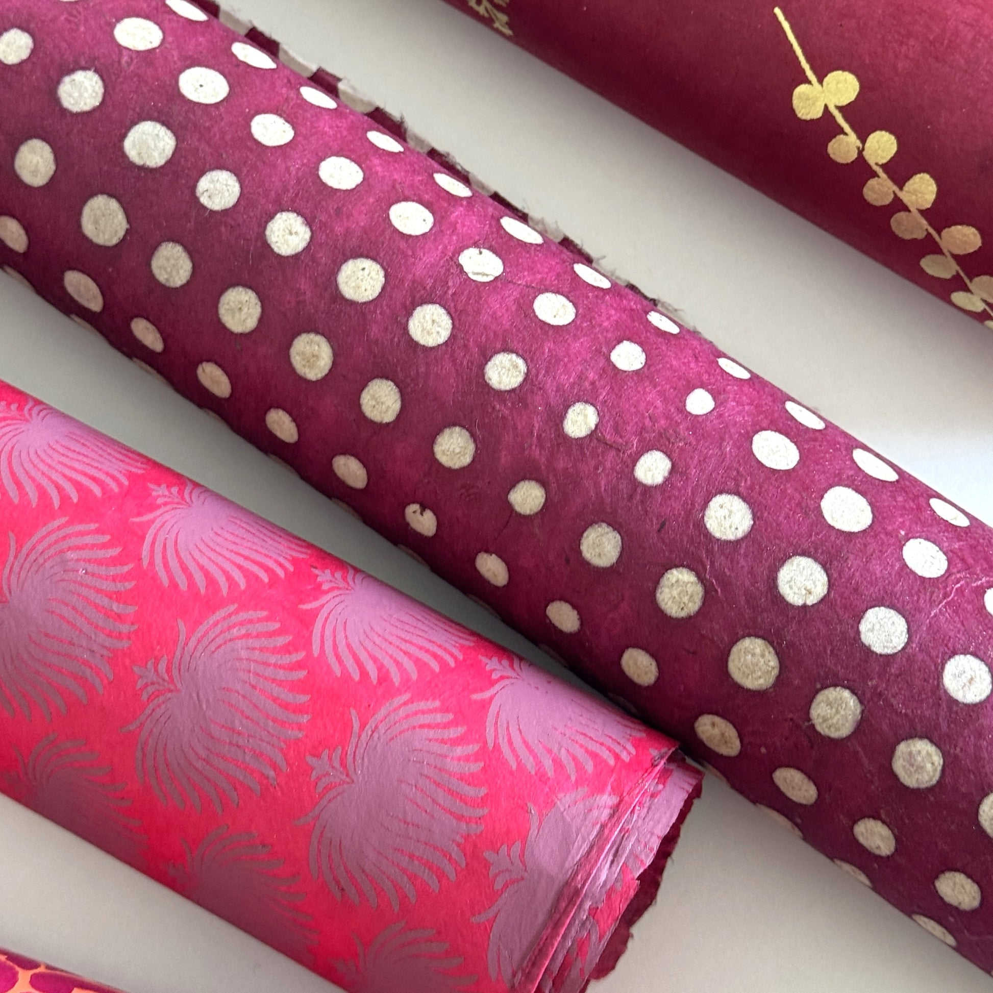 Nepalese handmade decorative lokta paper sheet with a pattern of white dots on burgundy red lokta paper.  Batik dyed using carved wooden blocks.