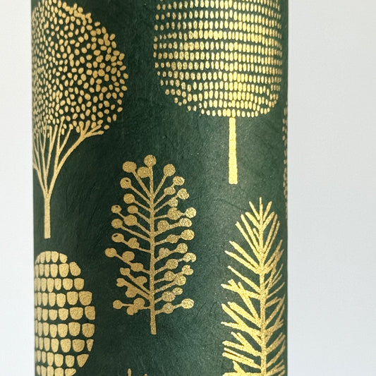 Nepalese handmade decorative lokta paper sheet with gold trees screen printed on a dark green lokta paper. Close up