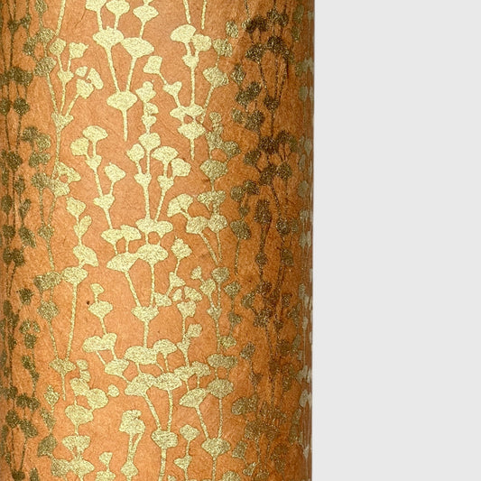 nepalese hand printed lokta paper with a small gold abstract gingko design on tan lokta paper. close up