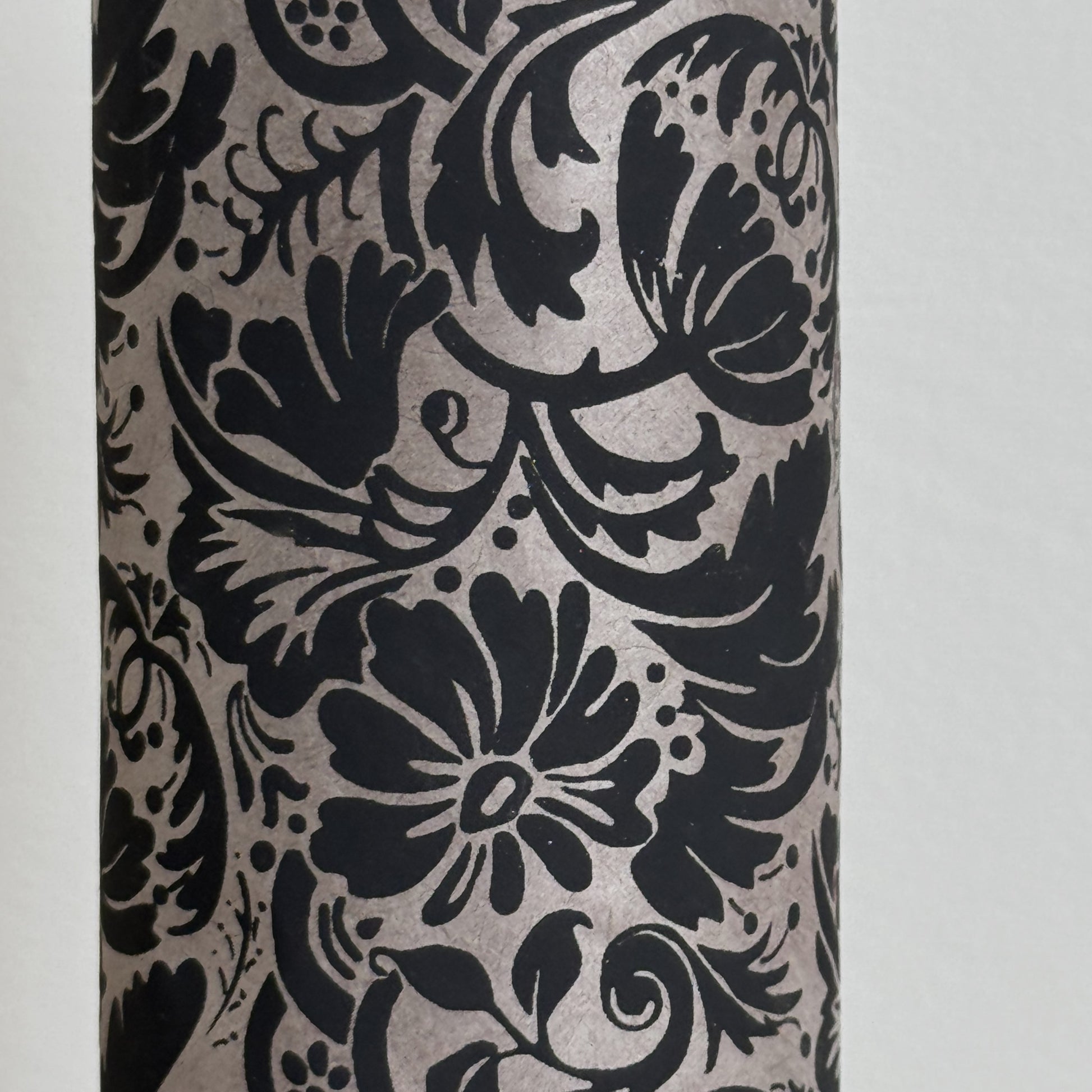 Nepalese handmade decorative lokta paper sheet with a black floral pattern screen printed on a dark taupe lokta paper. Close up