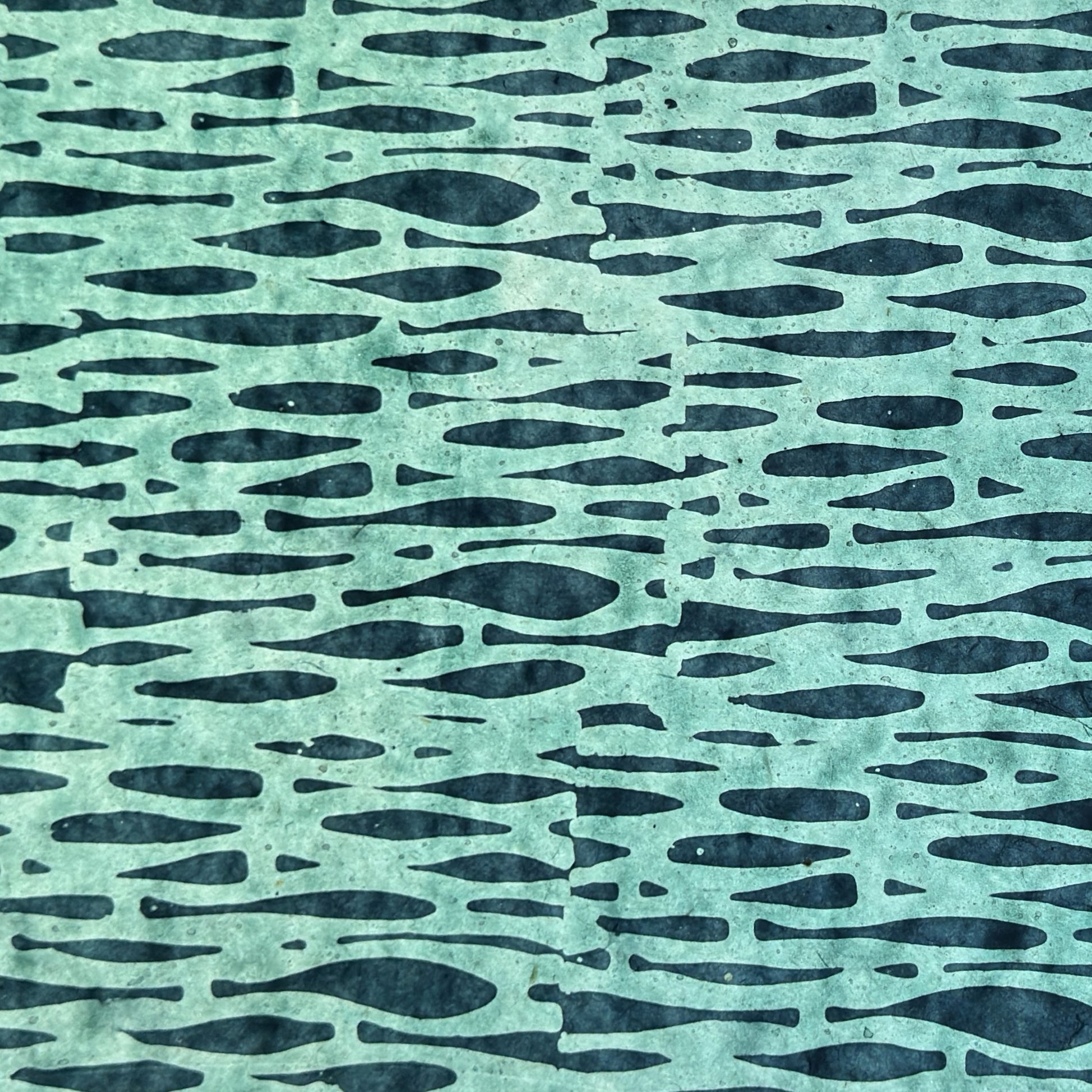 Nepalese handmade decorative lokta paper sheet with an abstract pattern in aqua and teal.  Batik dyed using carved wooden blocks. Pictured again light to show the translucent nature