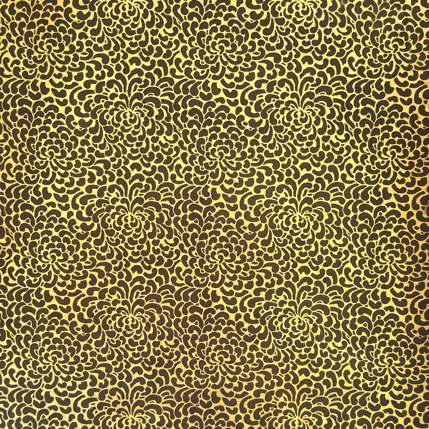 Nepalese handmade decorative lokta paper sheet with a gold screen printed floral design on a brown dyed lokta paper.