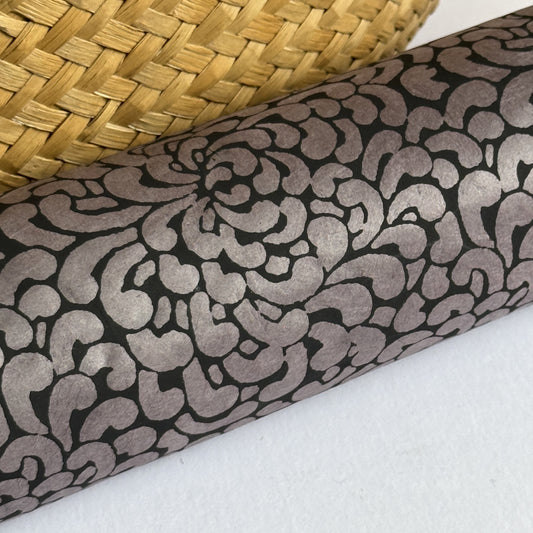 Nepalese handmade lokta paper sheet with a screen printed black floral design on slate lokta paper. close up