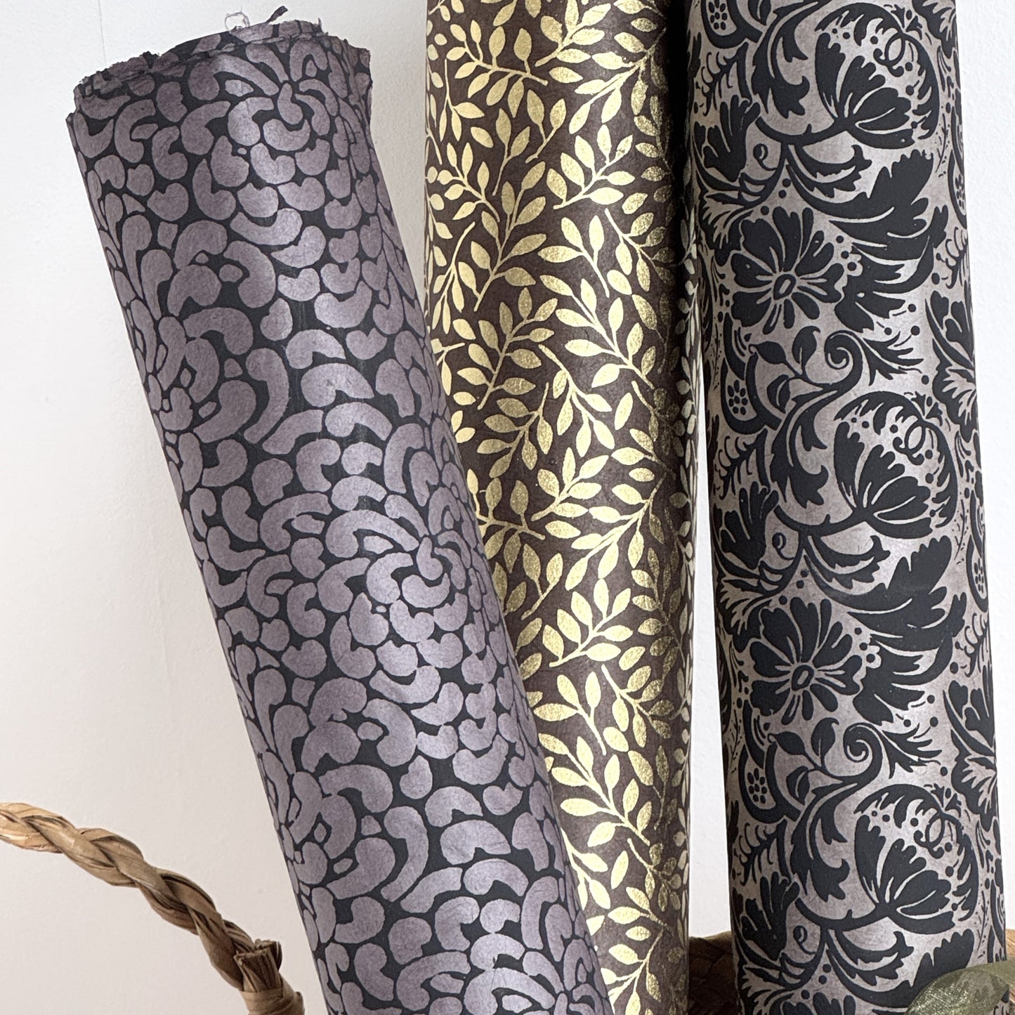 Nepalese handmade lokta paper sheet with a screen printed black floral design on slate lokta paper. Rolled with other designs.