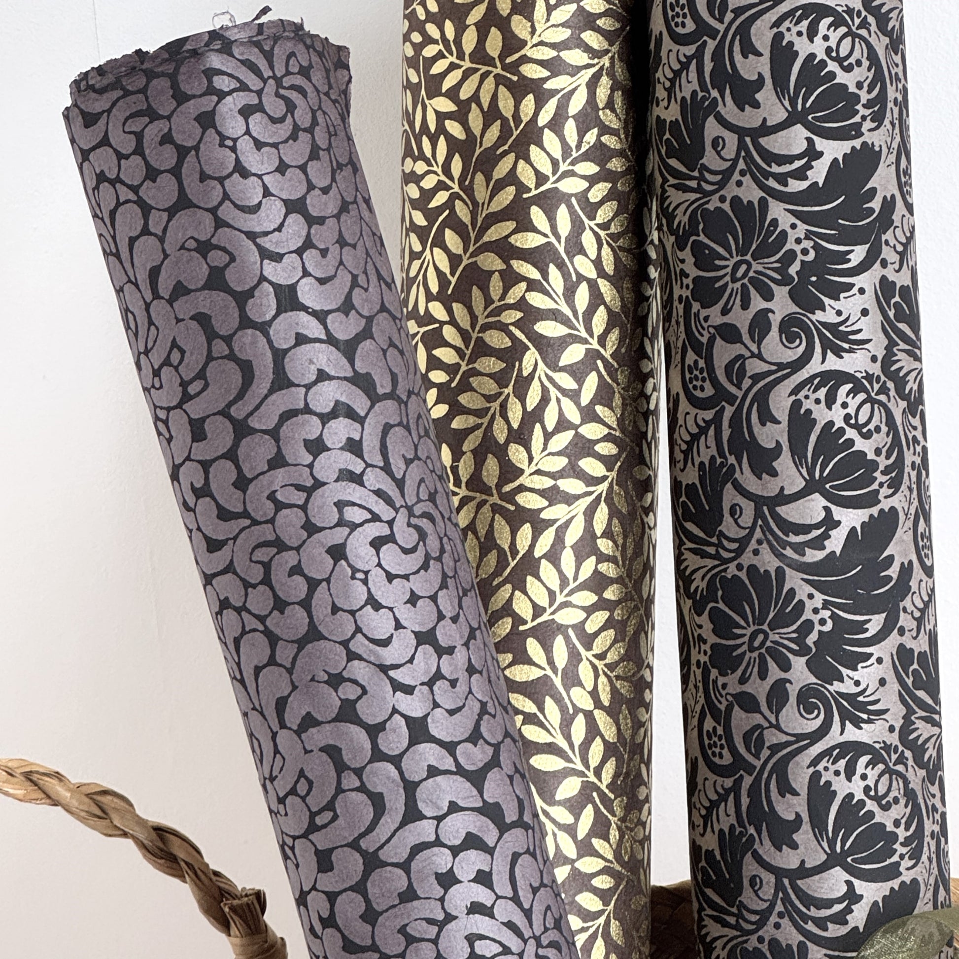 Nepalese handmade lokta paper sheet with a screen printed black floral design on slate lokta paper. Rolled with other designs.