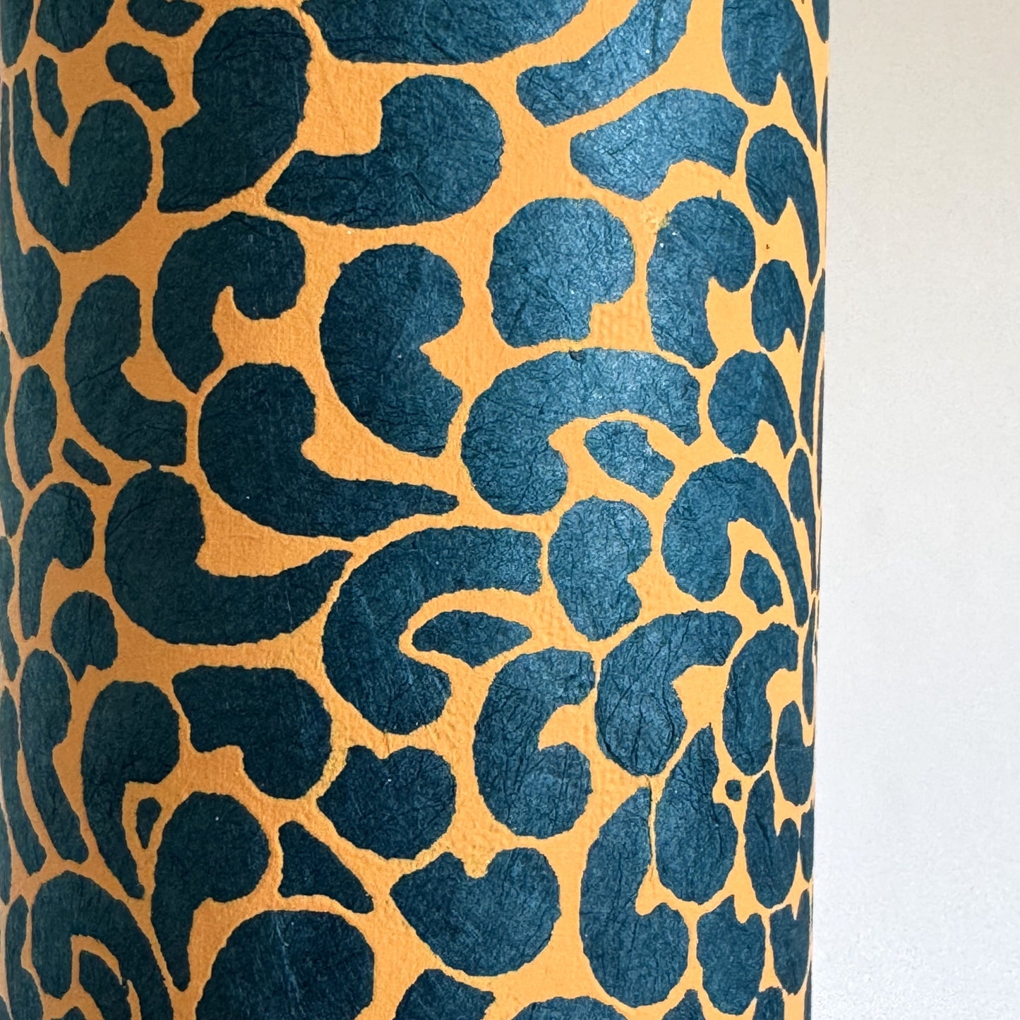 Nepalese handmade decorative lokta paper sheet with a saffron floral print screen printed on a teal lokta paper. Close up