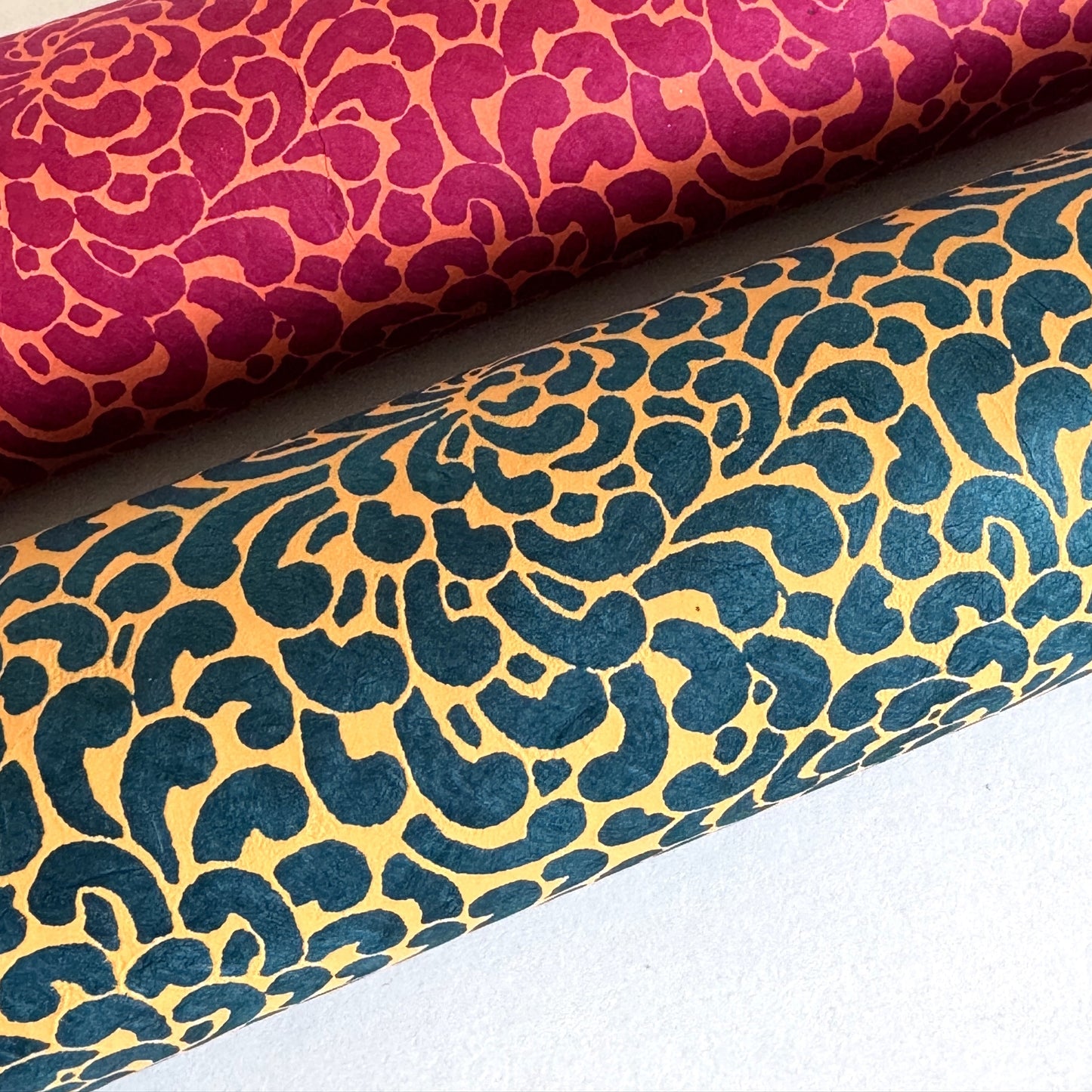 Nepalese handmade decorative lokta paper sheet with a saffron floral print screen printed on a teal lokta paper. Rolled