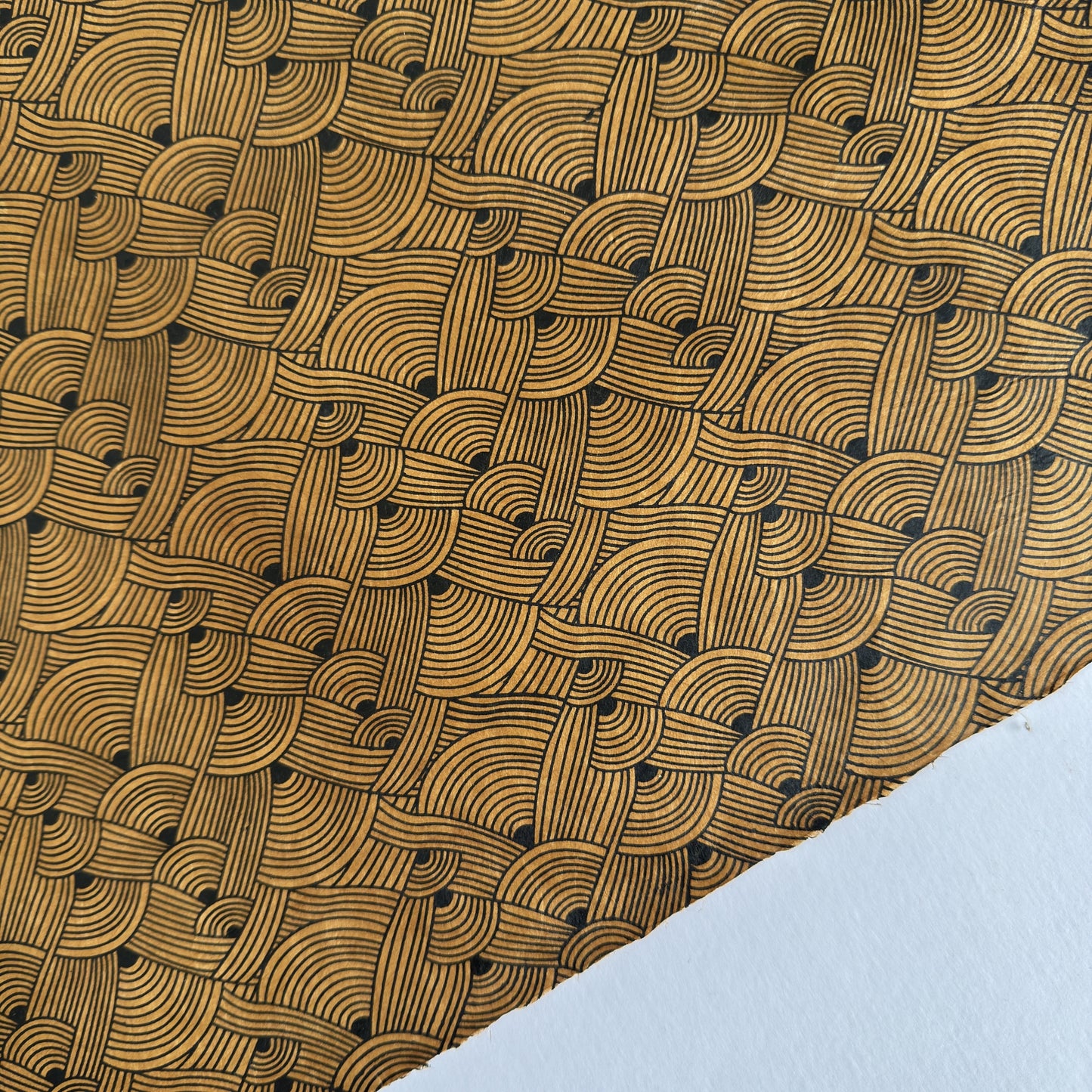 Nepalese handmade decorative lokta paper sheet with a fine lined black knots pattern screen printed on a brown lokta paper.