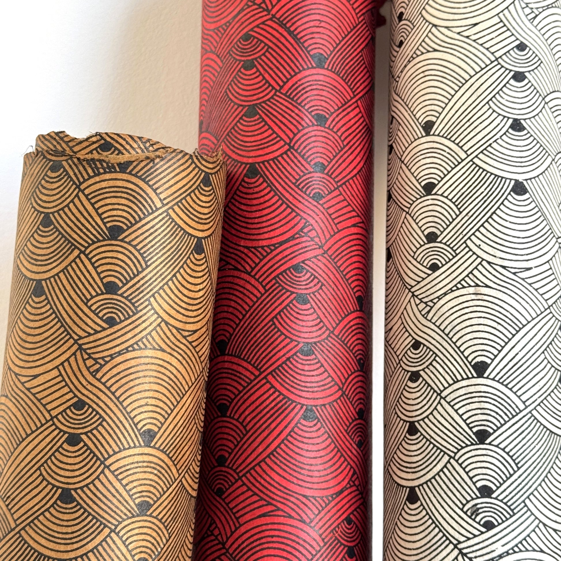 Nepalese handmade decorative lokta paper sheet with a fine lined black knots pattern screen printed on an ivory lokta paper. Pictured rolled alongside other colourways